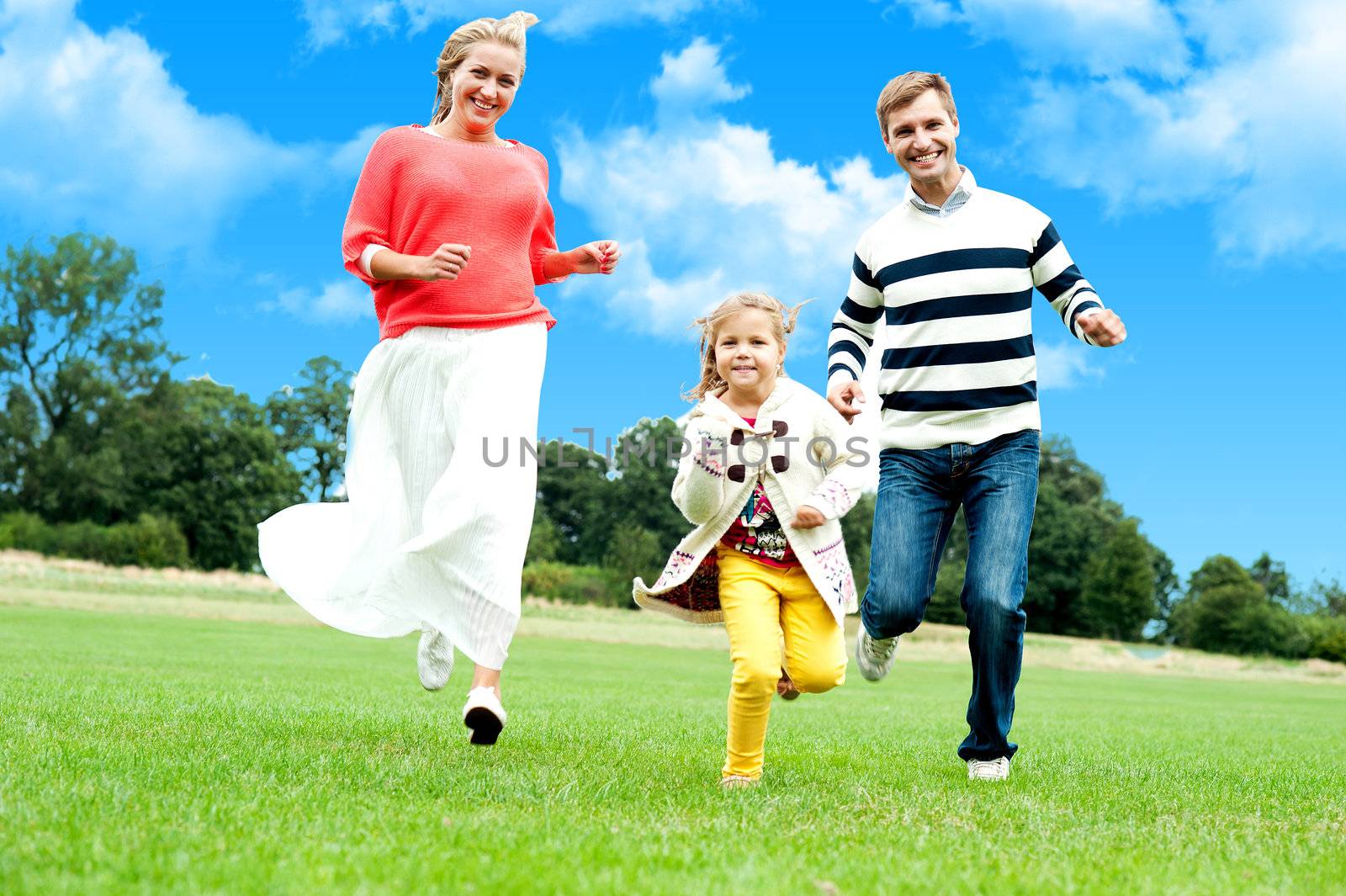 Young couple racing with their cute little daughter. Running in park