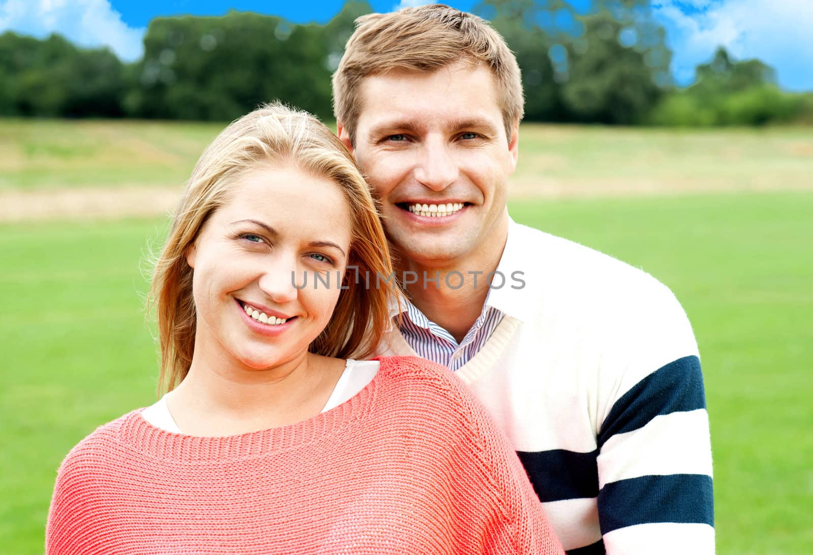 Young man standing behind his wife and hugging. Outdoor shot