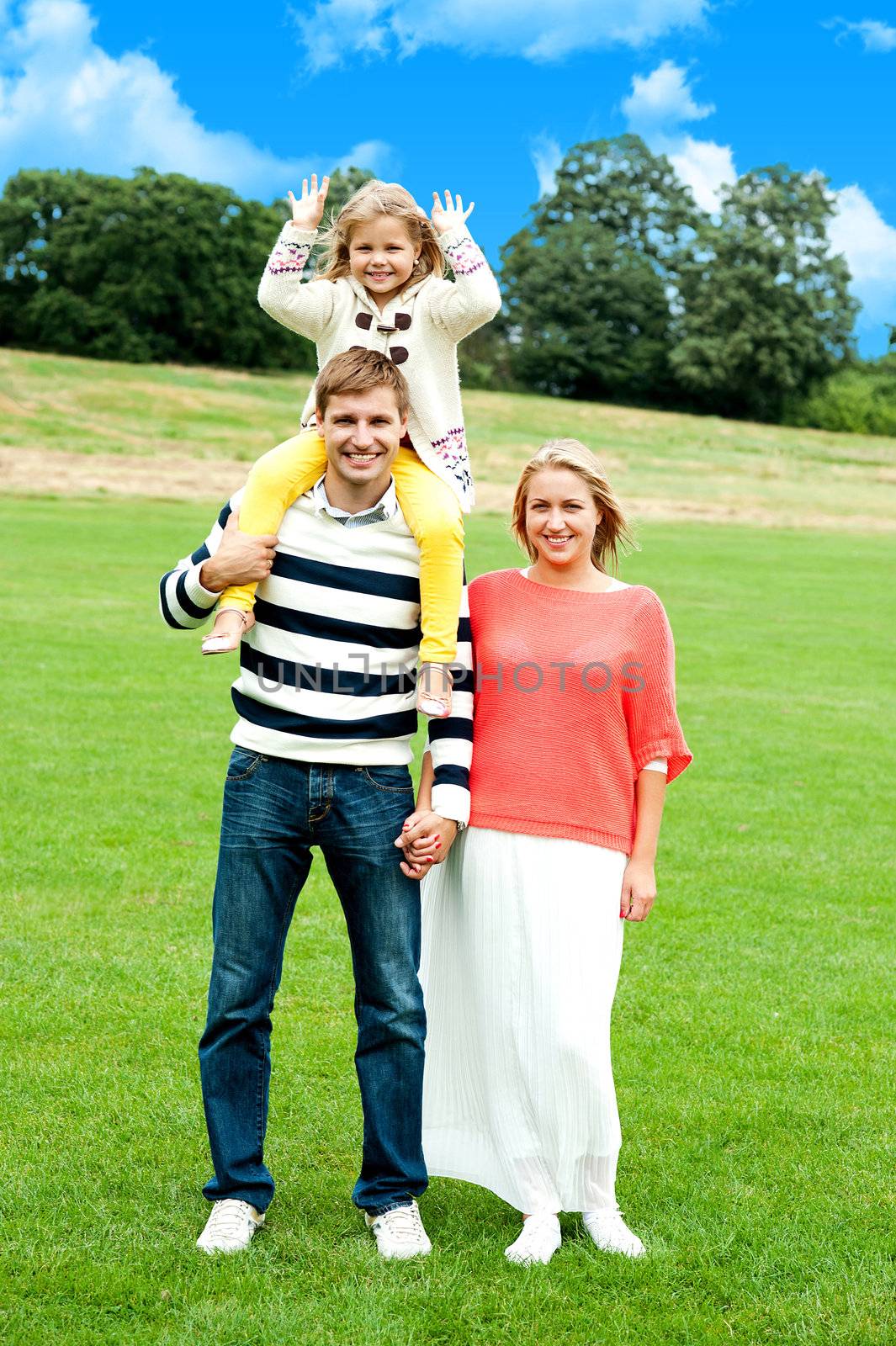 Full length portrait of adorable family of three posing against natural background