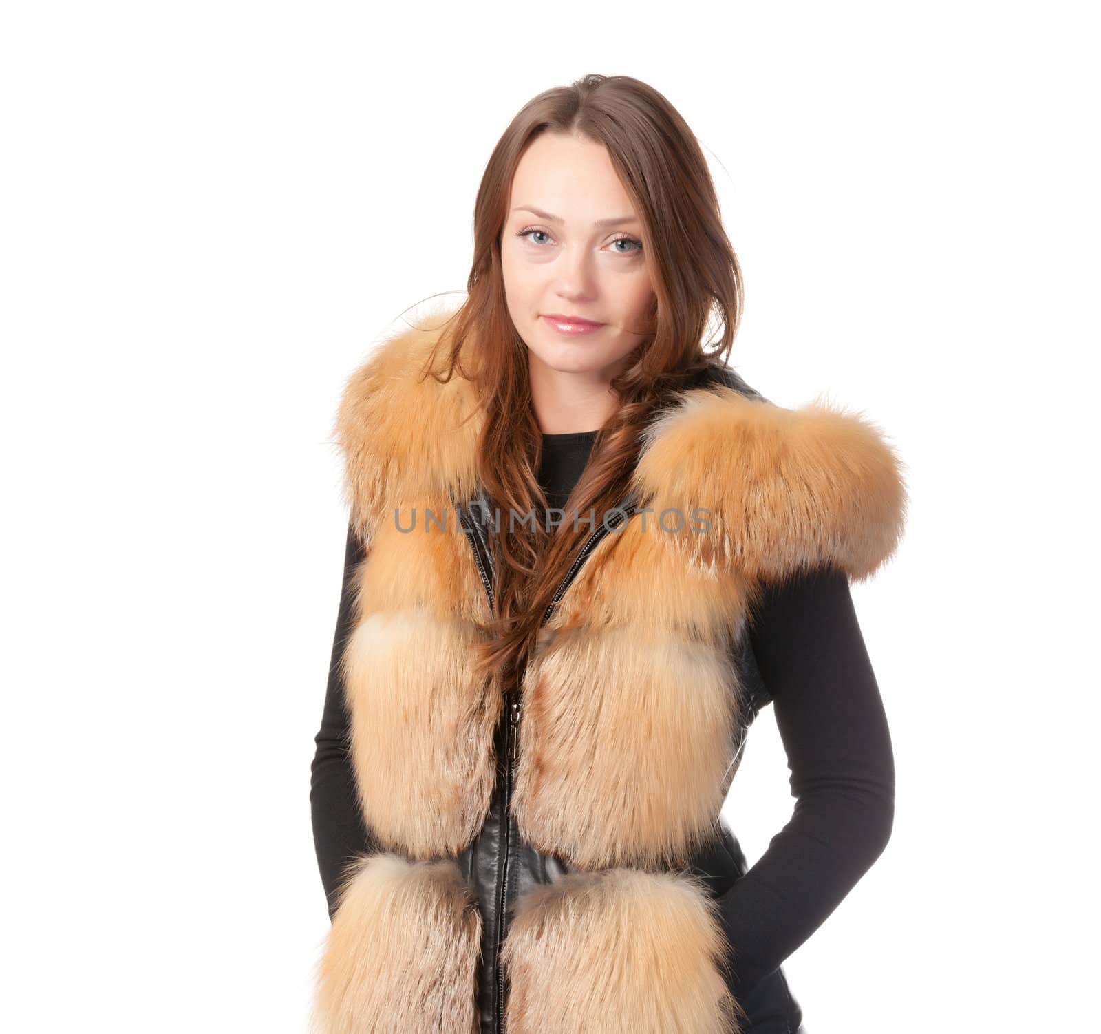 Stylish relaxed young woman in winter fur jacket standing with her hands in her pocket isolated on white