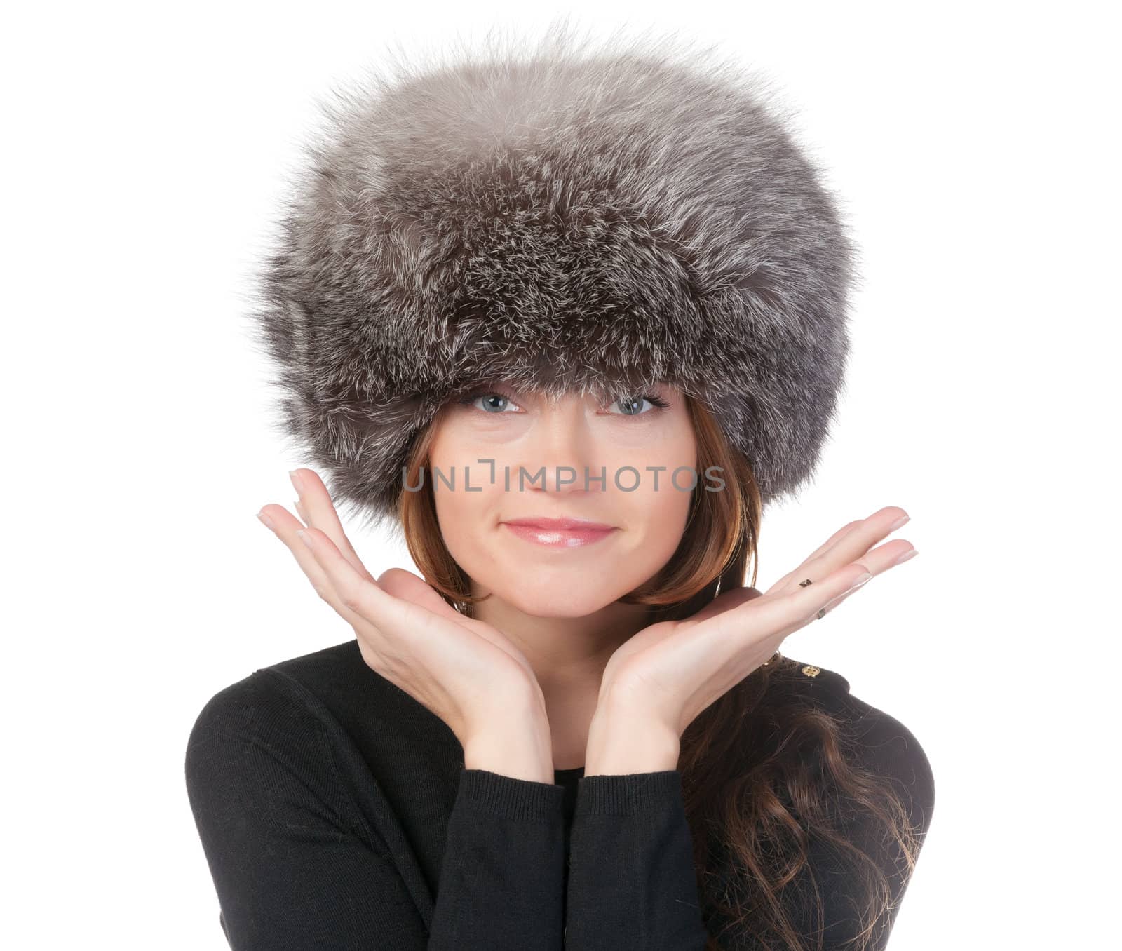 Glamorous woman in winter fashion standing with her hands raised to her fur hat isolated on white