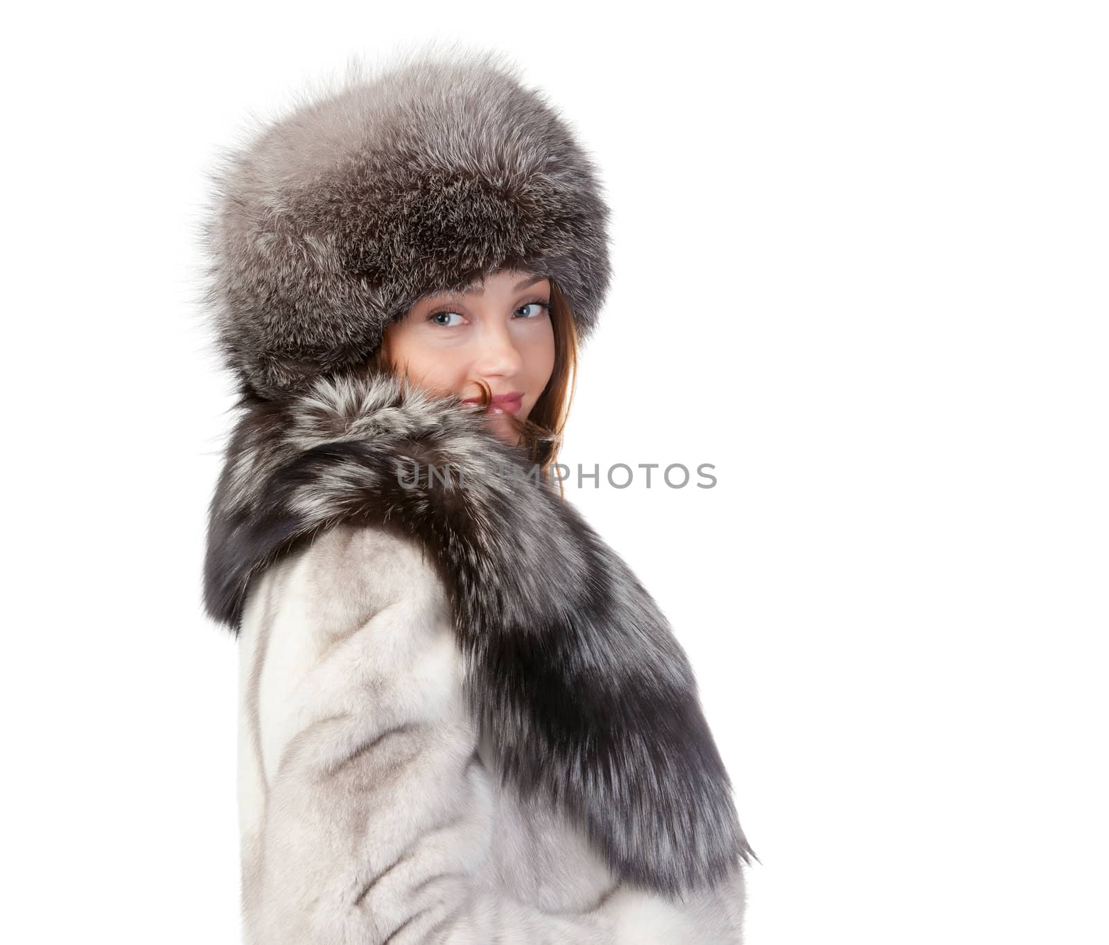 Sexy woman wearing a stylish winter fur coat and hat for protection against the bitter cold on a white background