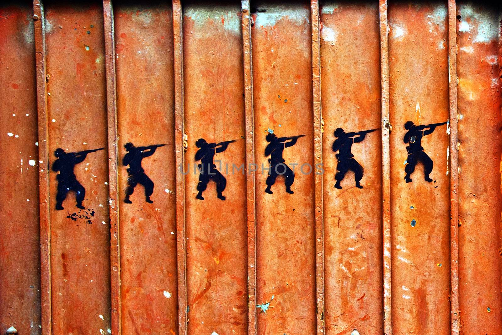 Graffiti of soldiers with guns on an old metal door.