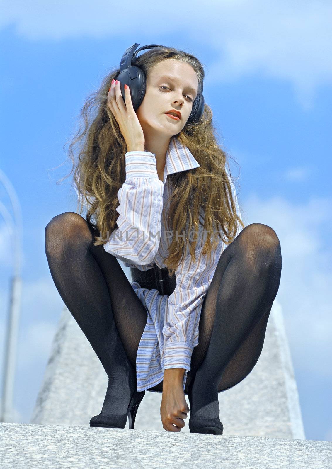 Happy girl listening music on blue sky background