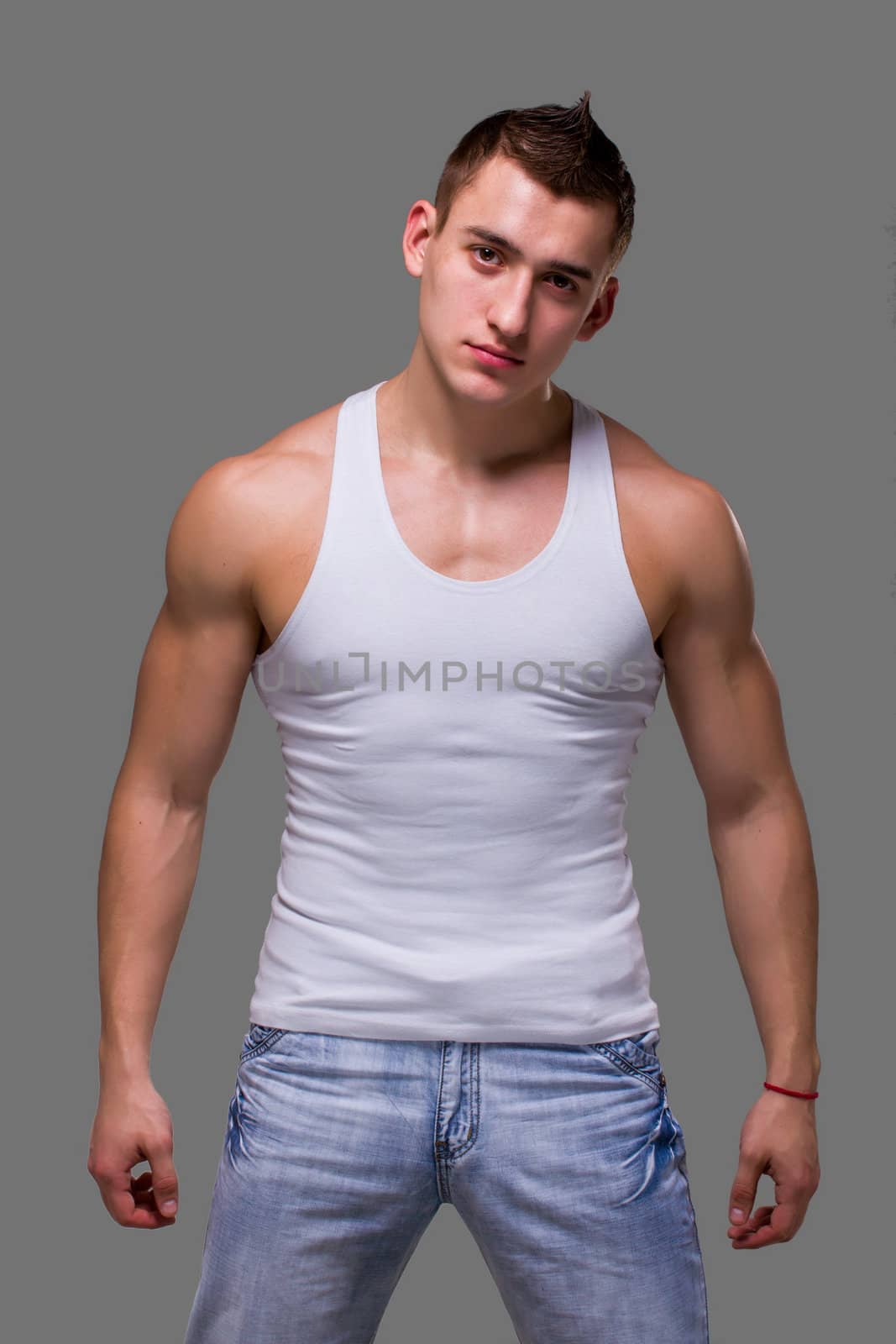 Muscular man posing on a gray background