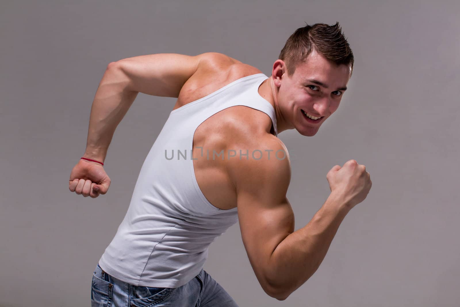 Smiling muscular man posing on a gray background