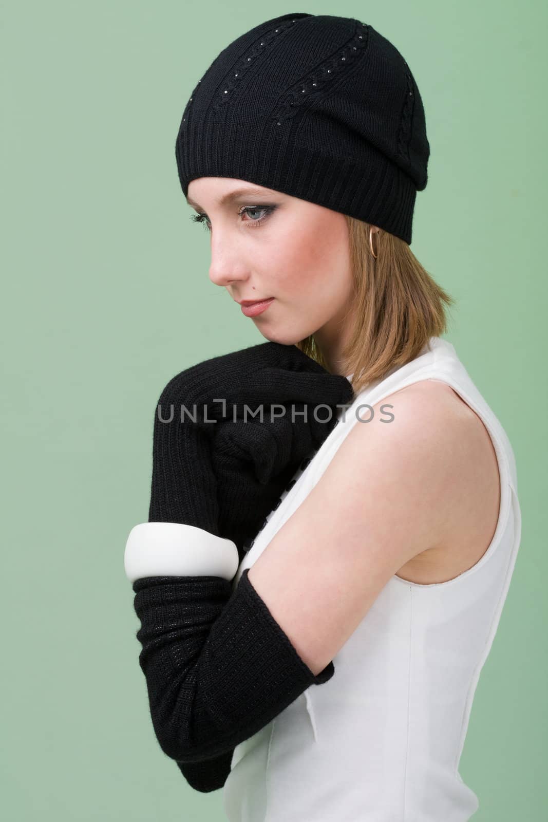 knitwear. young woman wearing a winter cap and gloves on a green background