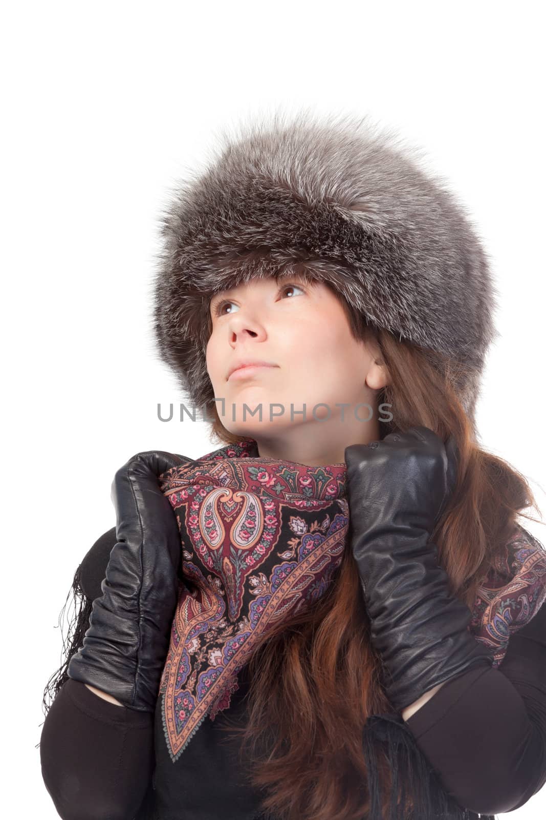 Elegant fashionable woman in winter outfit wearing a scarf, leather gloves and warm fur hat looking up into the sky deep in thought