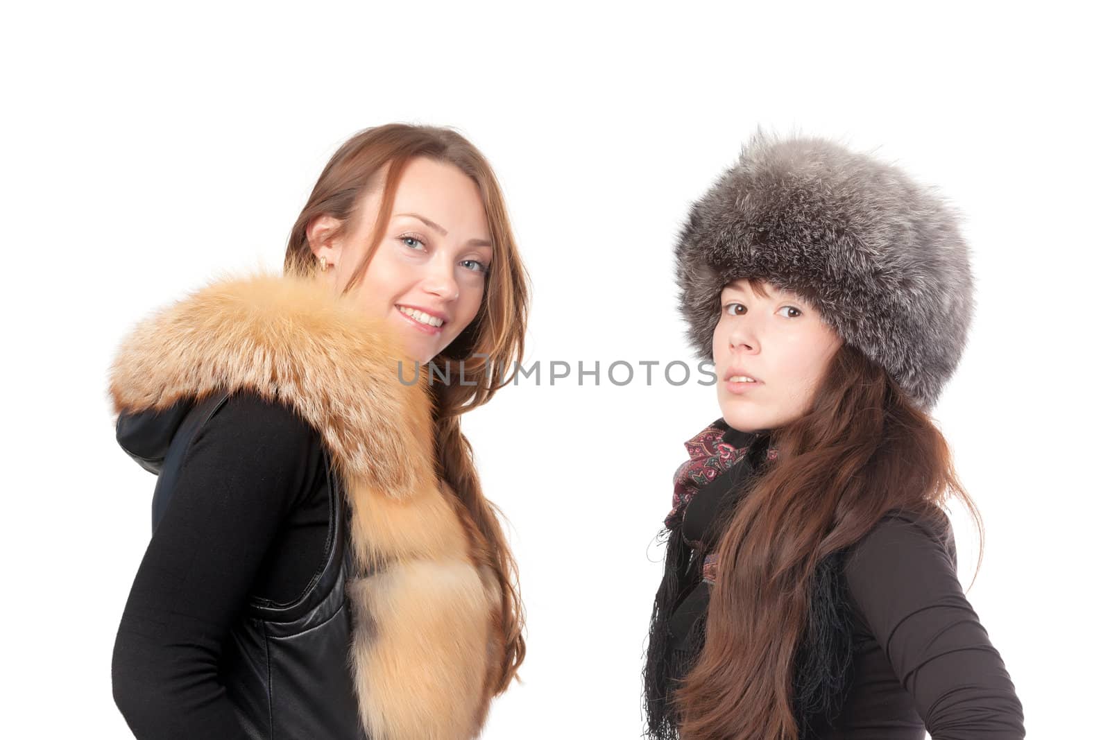 Two attractive women dressed for winter posing together on a white background in fur trimmed garments