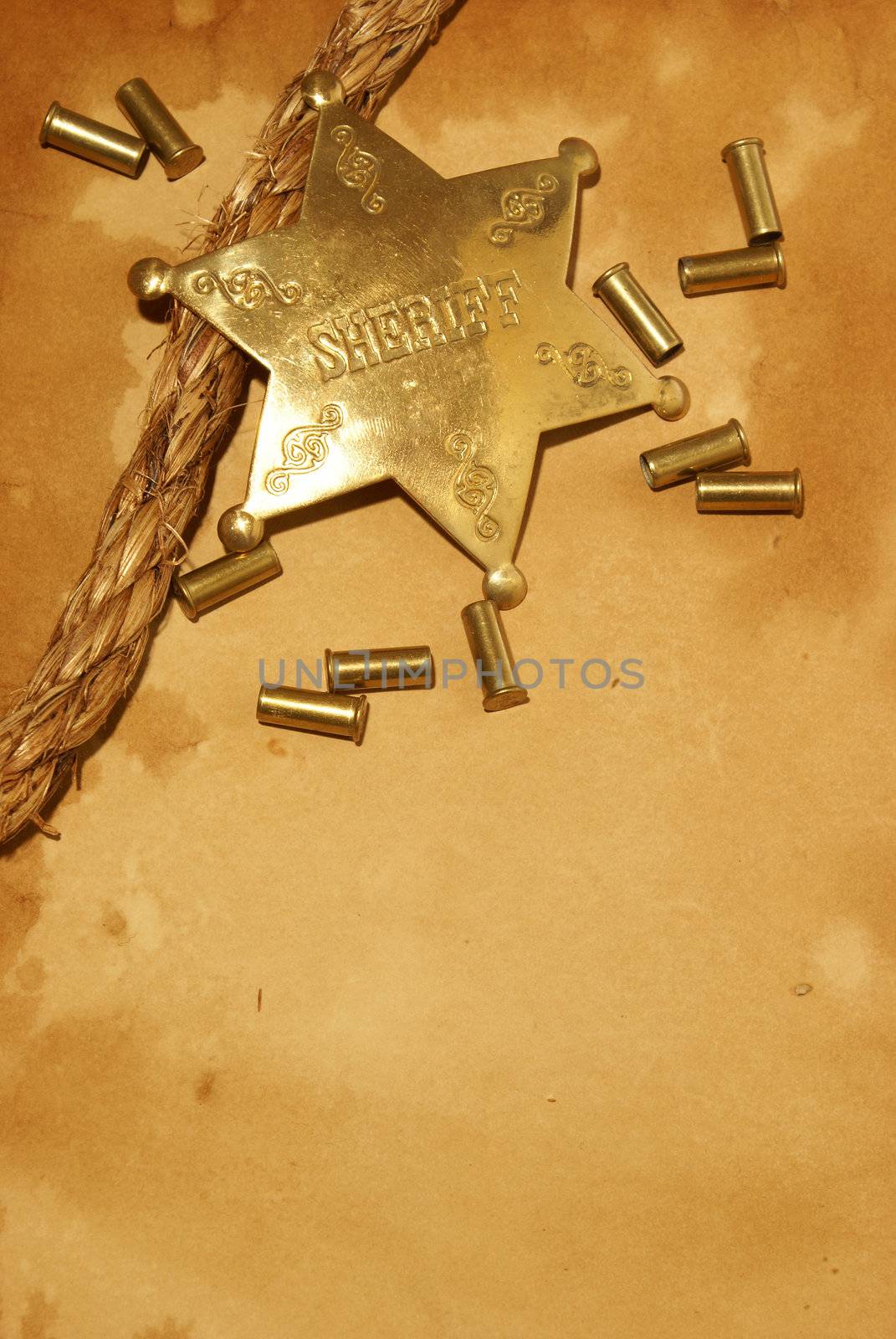 A sheriff badge and gun shells on some antique paper.