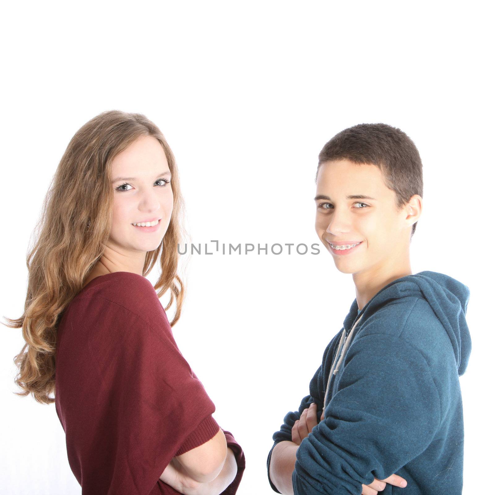Friendly attractive young teenage brother and sister standing sideways facing each other in casual tops with their arms folded looking at the camera isolated on white Friendly attractive young teenage siblings standing sideways facing each other in casual tops with their arms folded looking at the camera isoalted on white