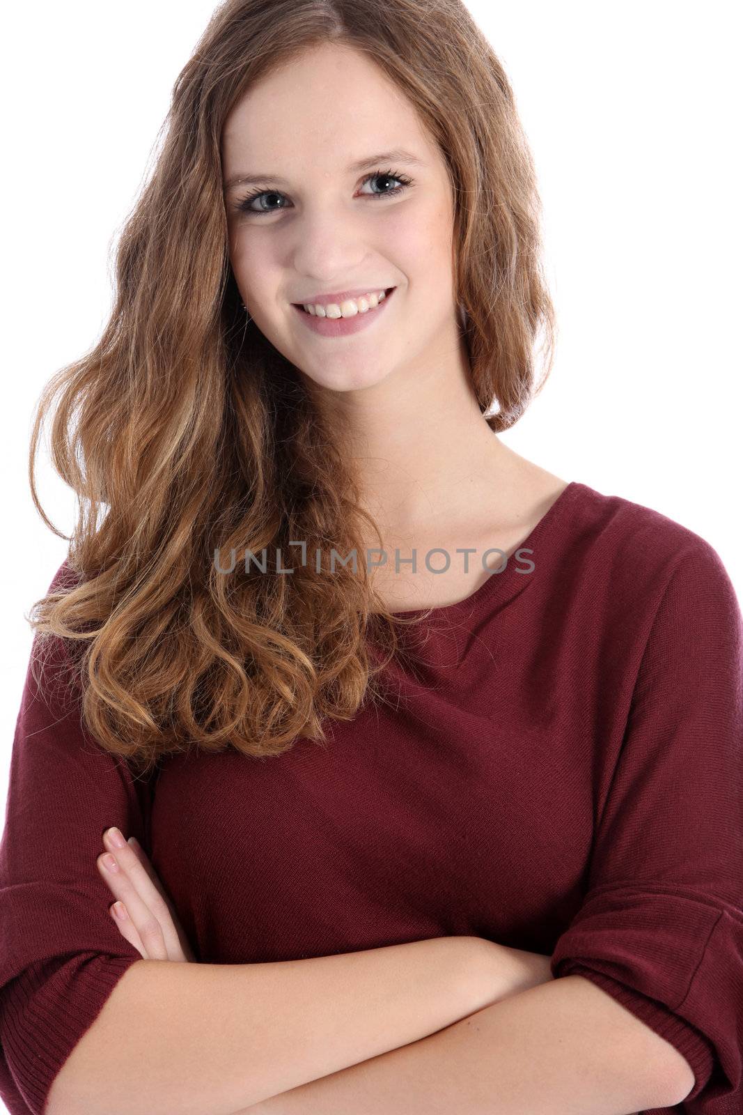 Beautiful smiling teenage girl with long curly hair standing with her arms folded facing the camera isolated on white