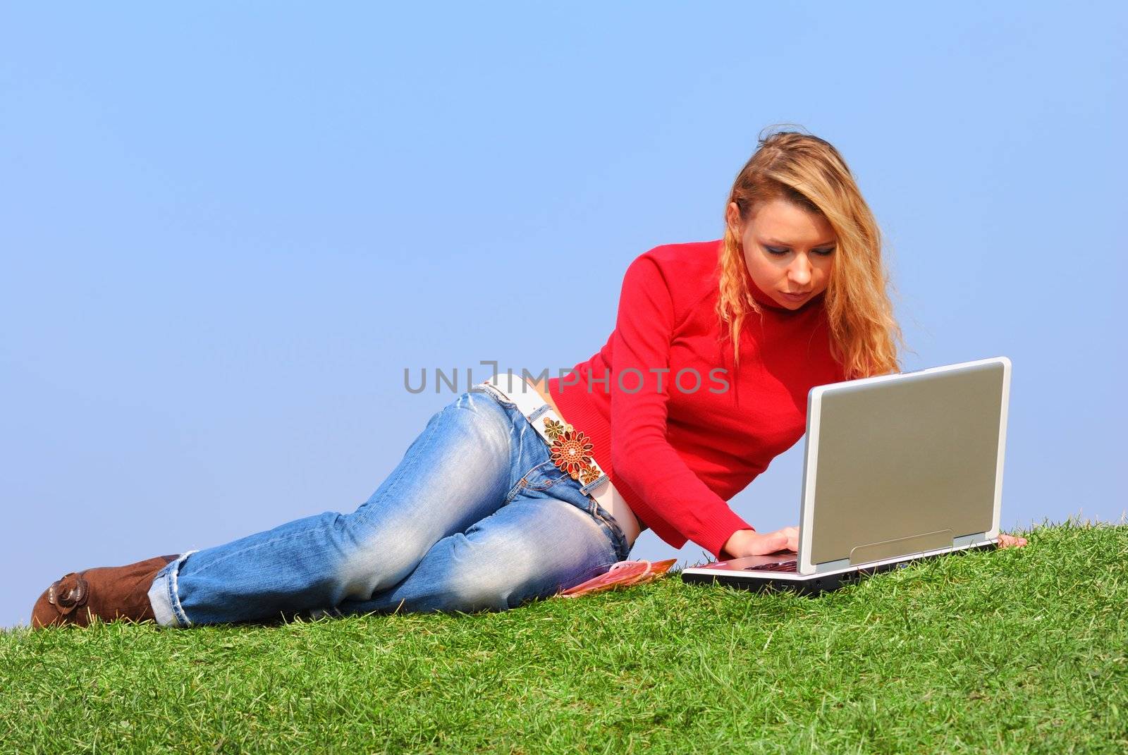 Girl with notebook sitting on grass against sky                                      