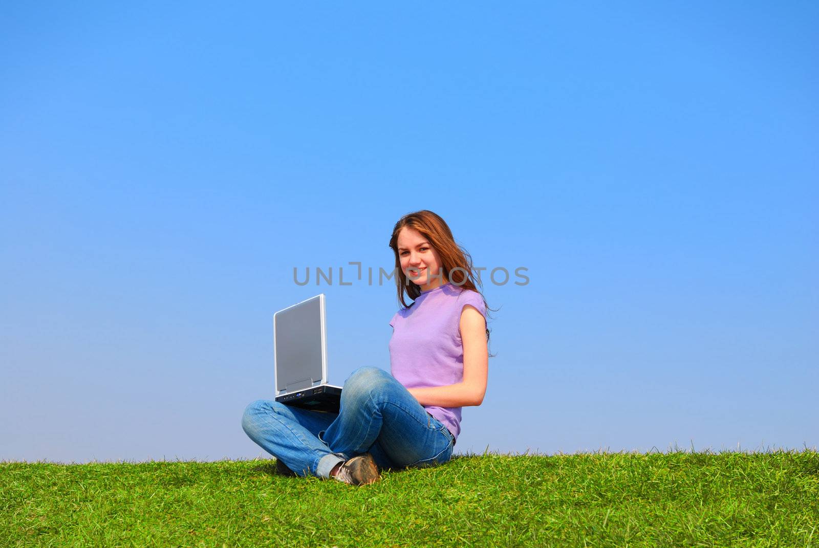 Girl with notebook sitting on grass against sky                                      