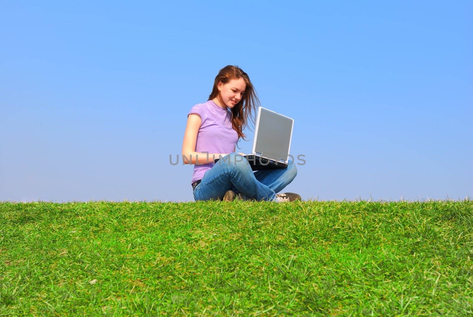 Girl with notebook sitting on grass against sky                                      