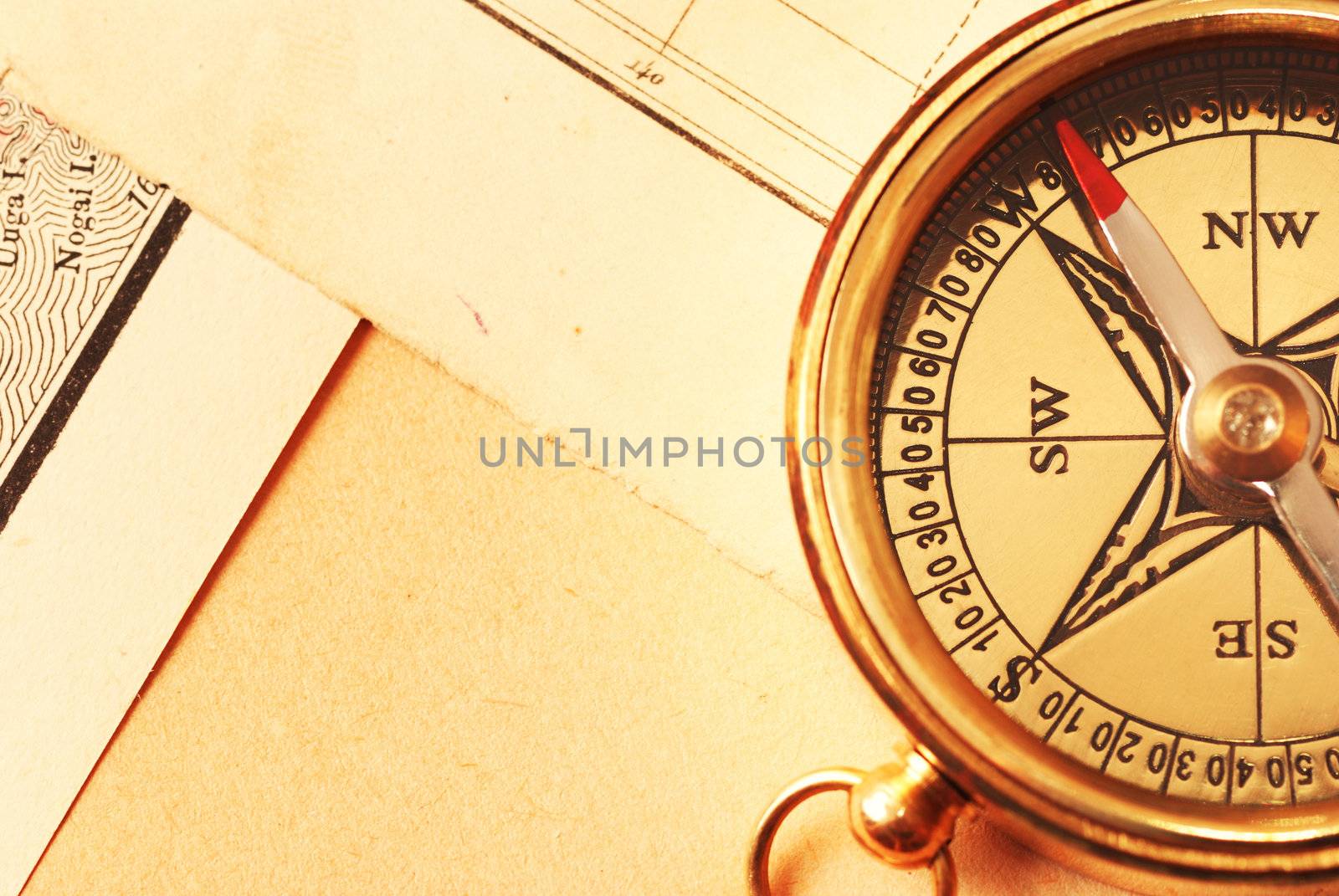 Antique brass compass over old map background                                    