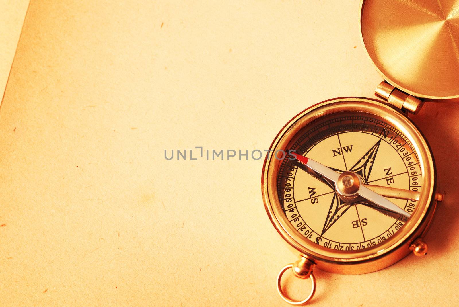 Antique brass compass over old map background  