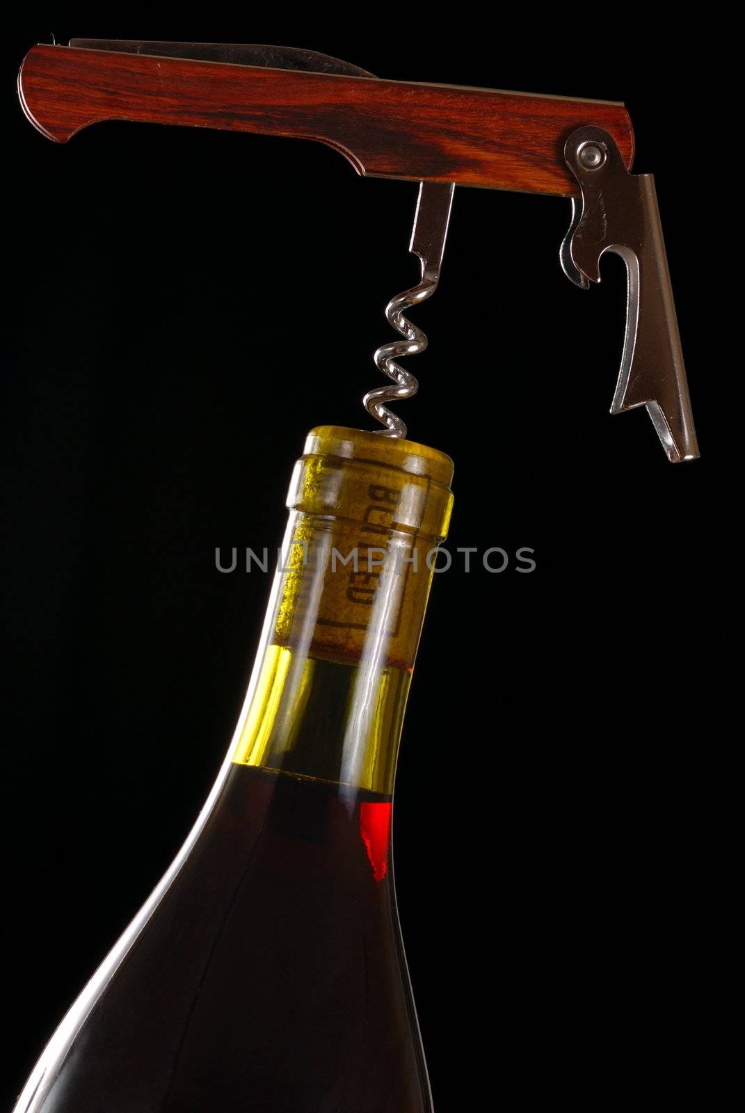 Opening a wine bottle with corkscrew, isolated on black