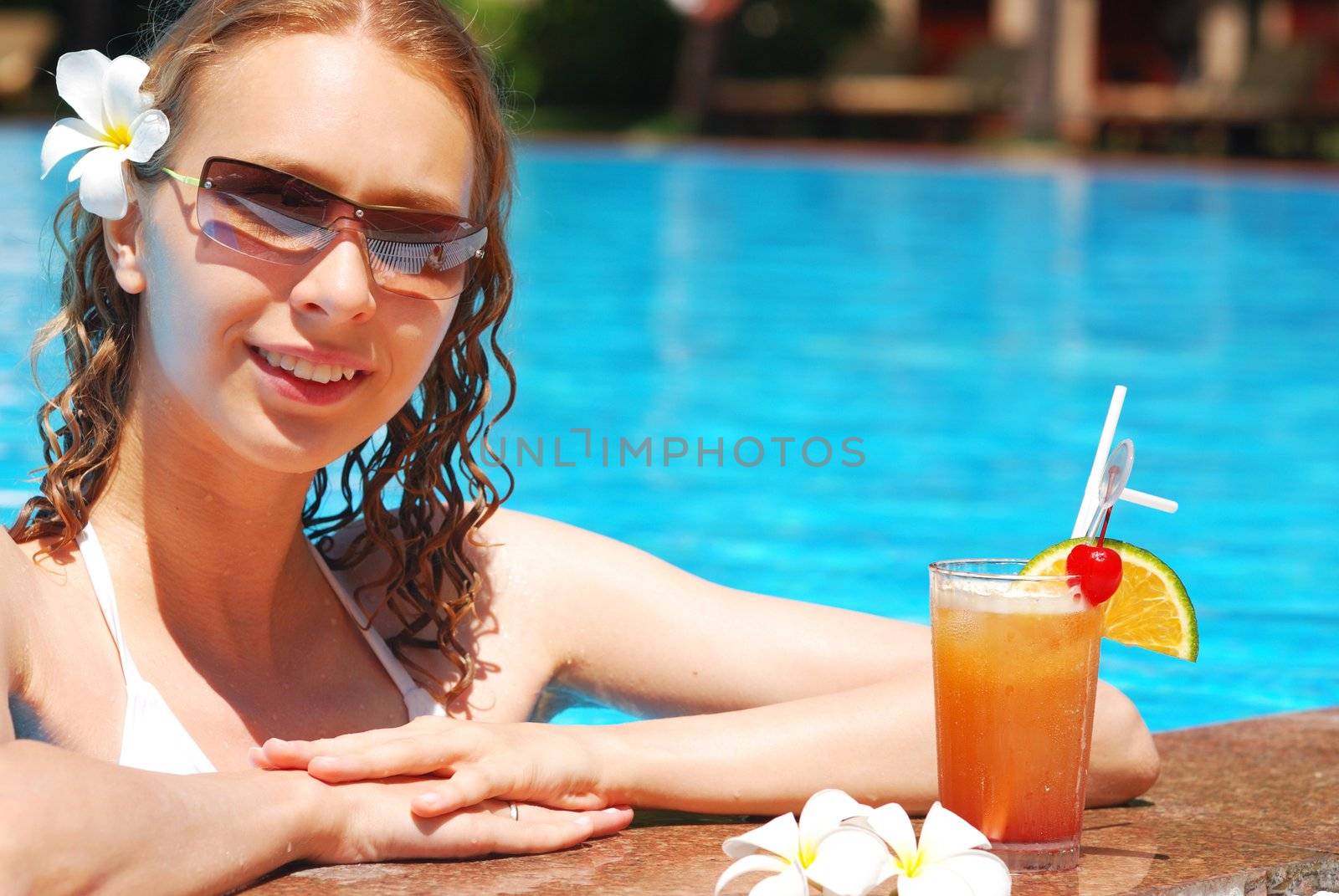 Girl in tropical pool with cocktail