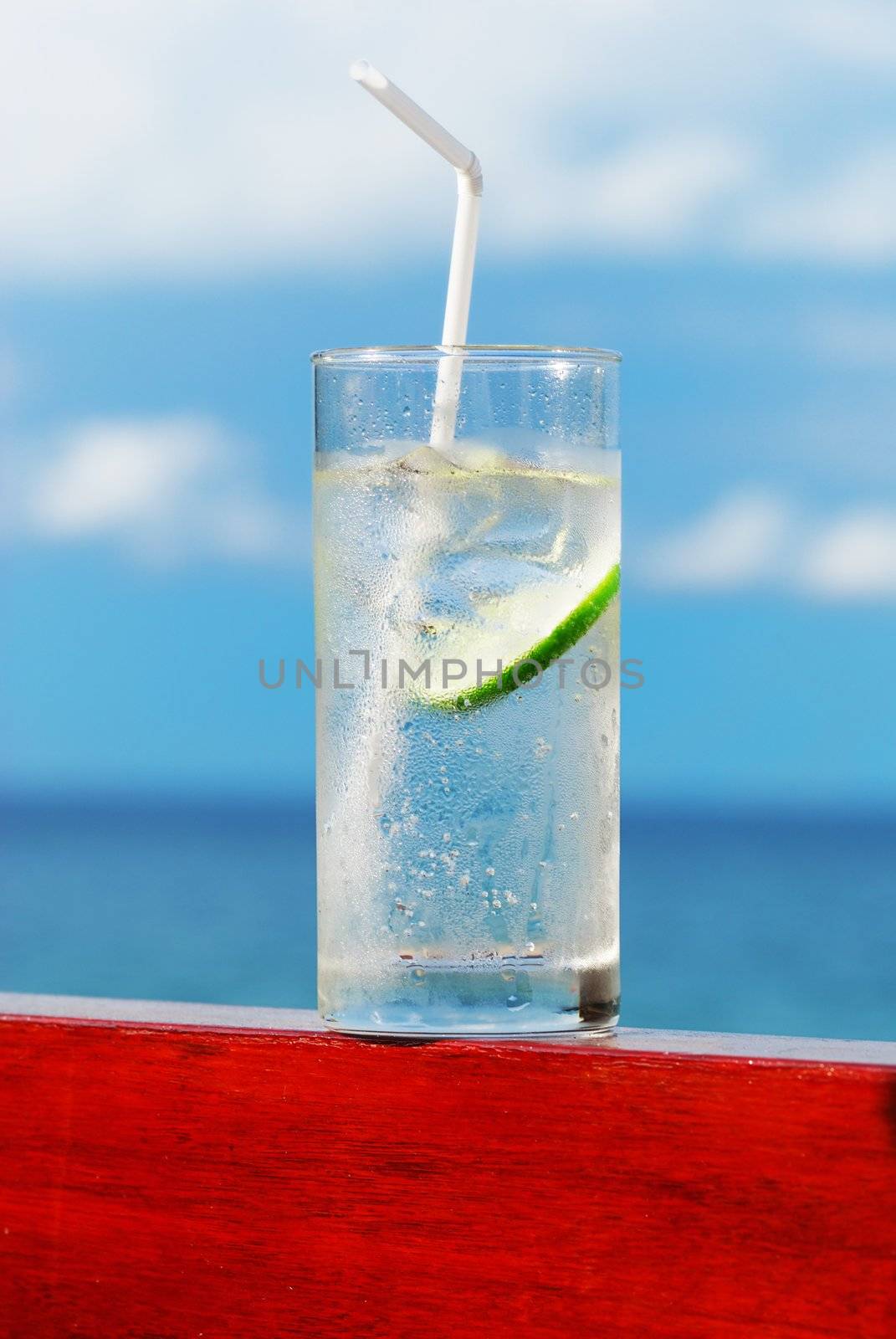 Glass of soda with lime. Sea in background.