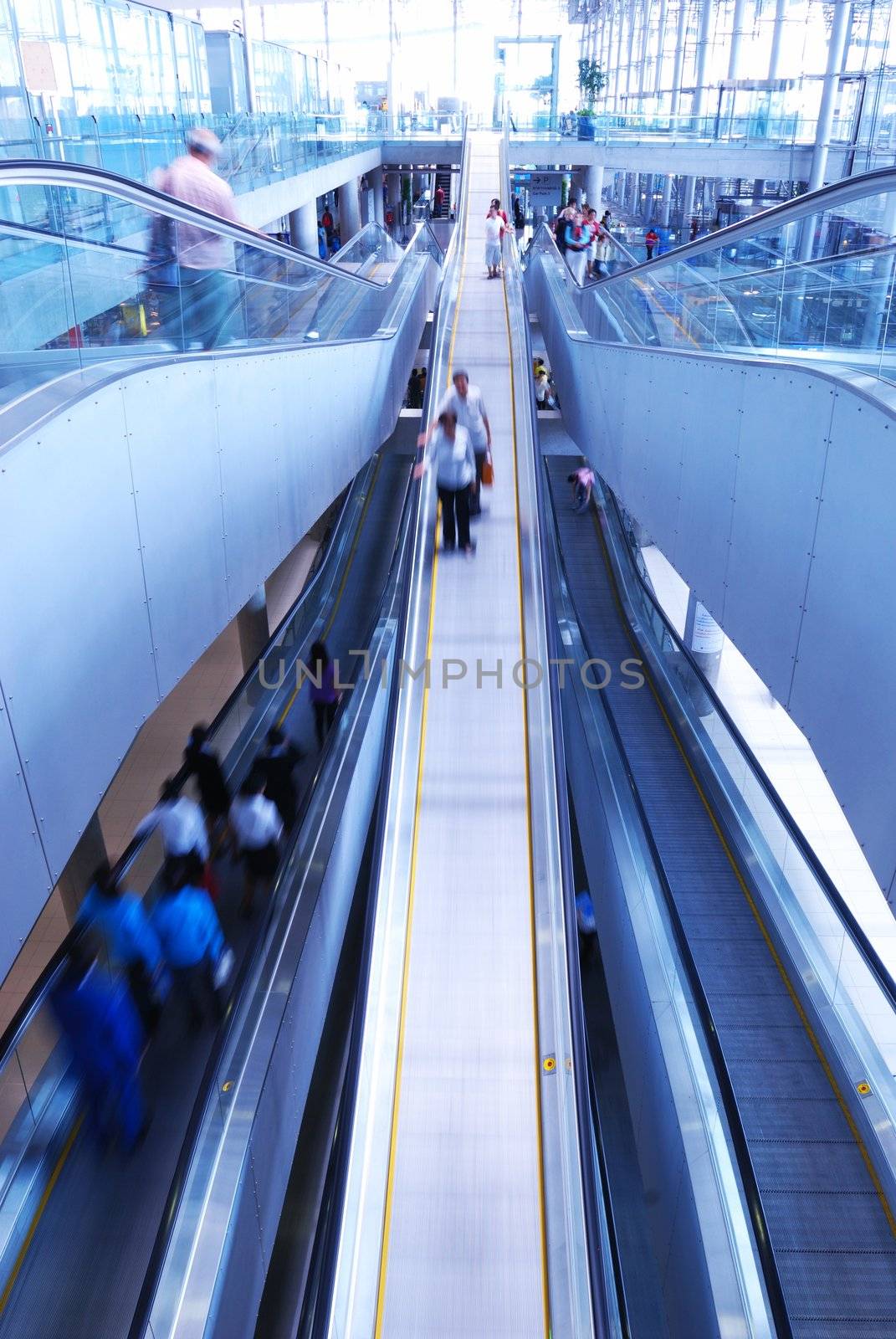 Travelator with people in airport. No recognizable faces or brandnames. Toned Cold.