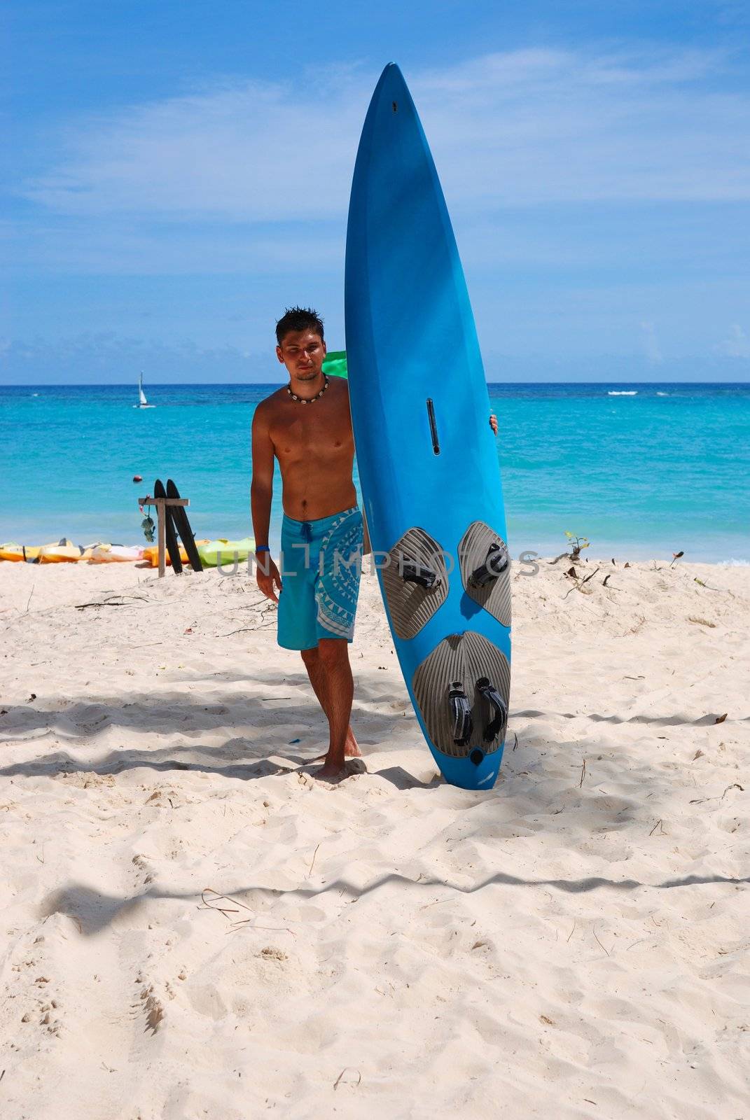 Man at the beach standing next to his surf