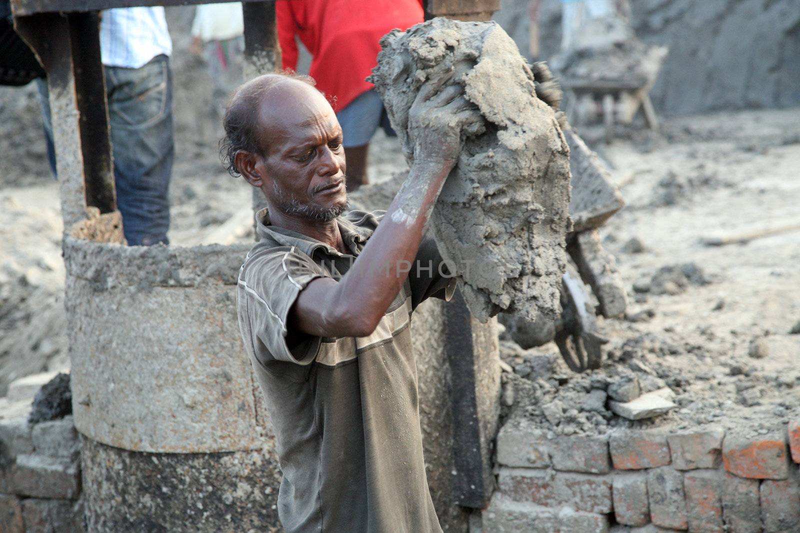 Laborers are carrying deposited soil for making raw brick by atlas