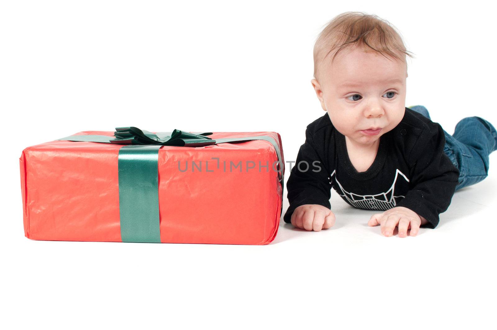 Beautiful baby boy lying near christmas present on white