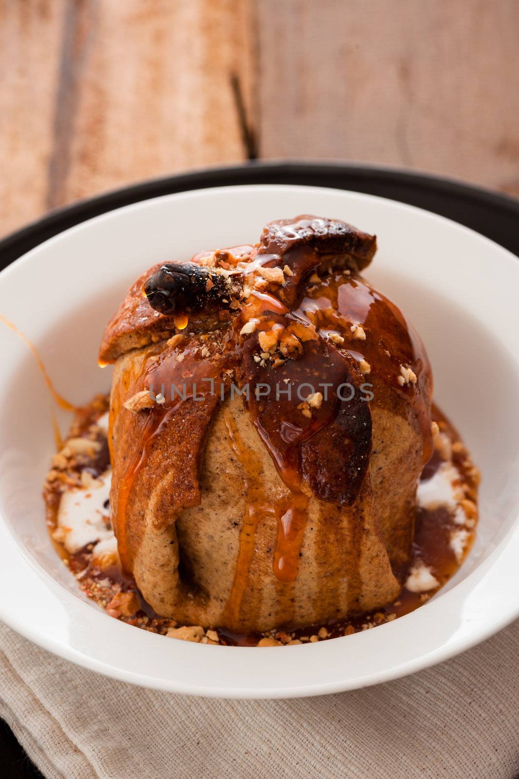 baked apple with a coat of cinnamon dough and an orange Grand Marnier sauce on wooden table as background