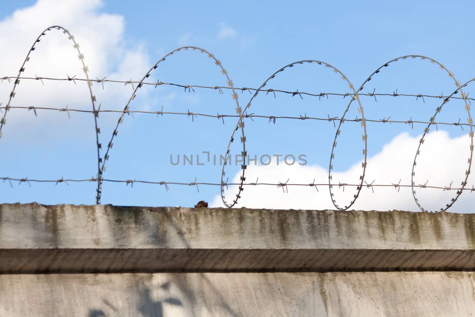 Wall with barbed wire on a background of blue sky