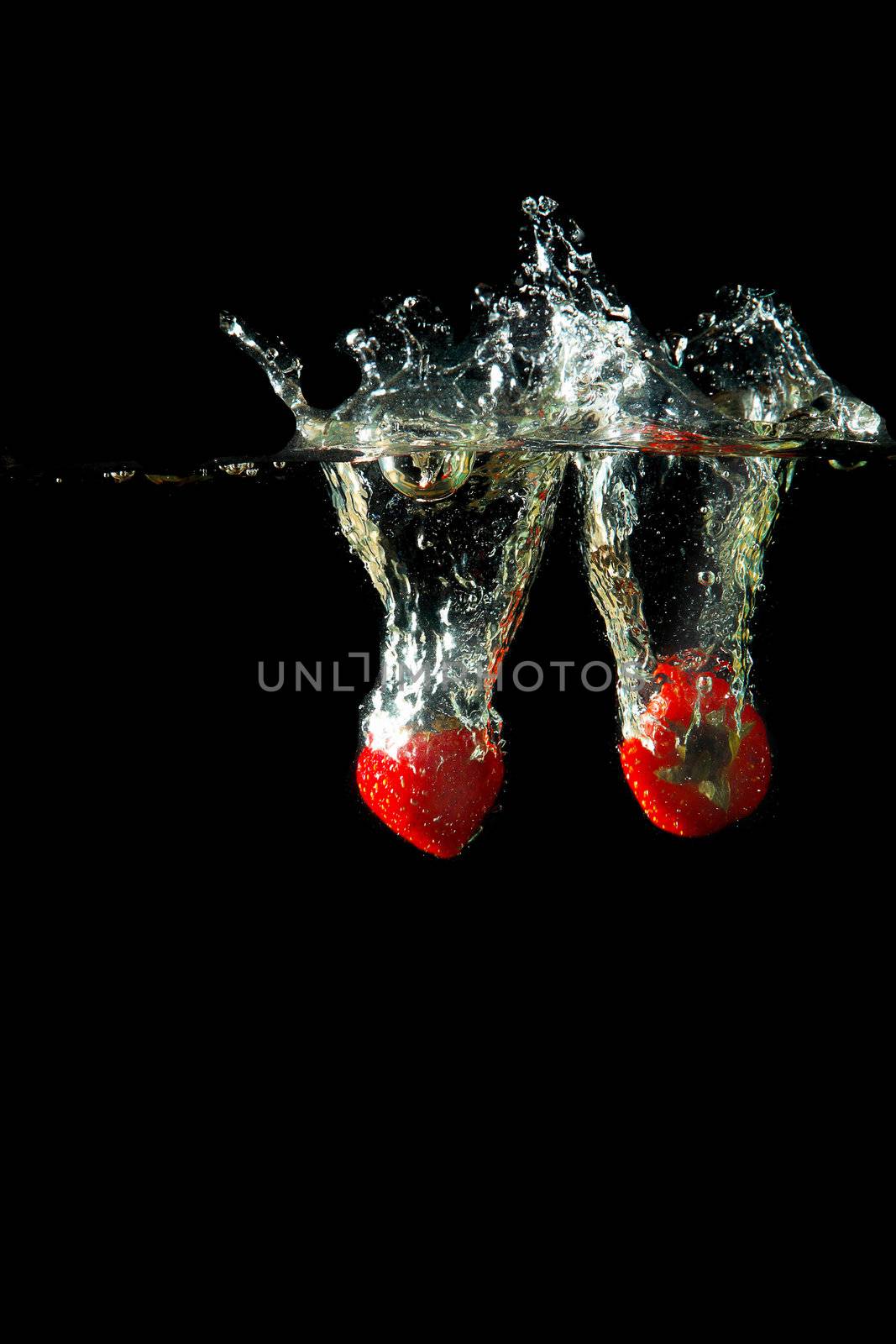 Colored red paprika in water splashes on black background