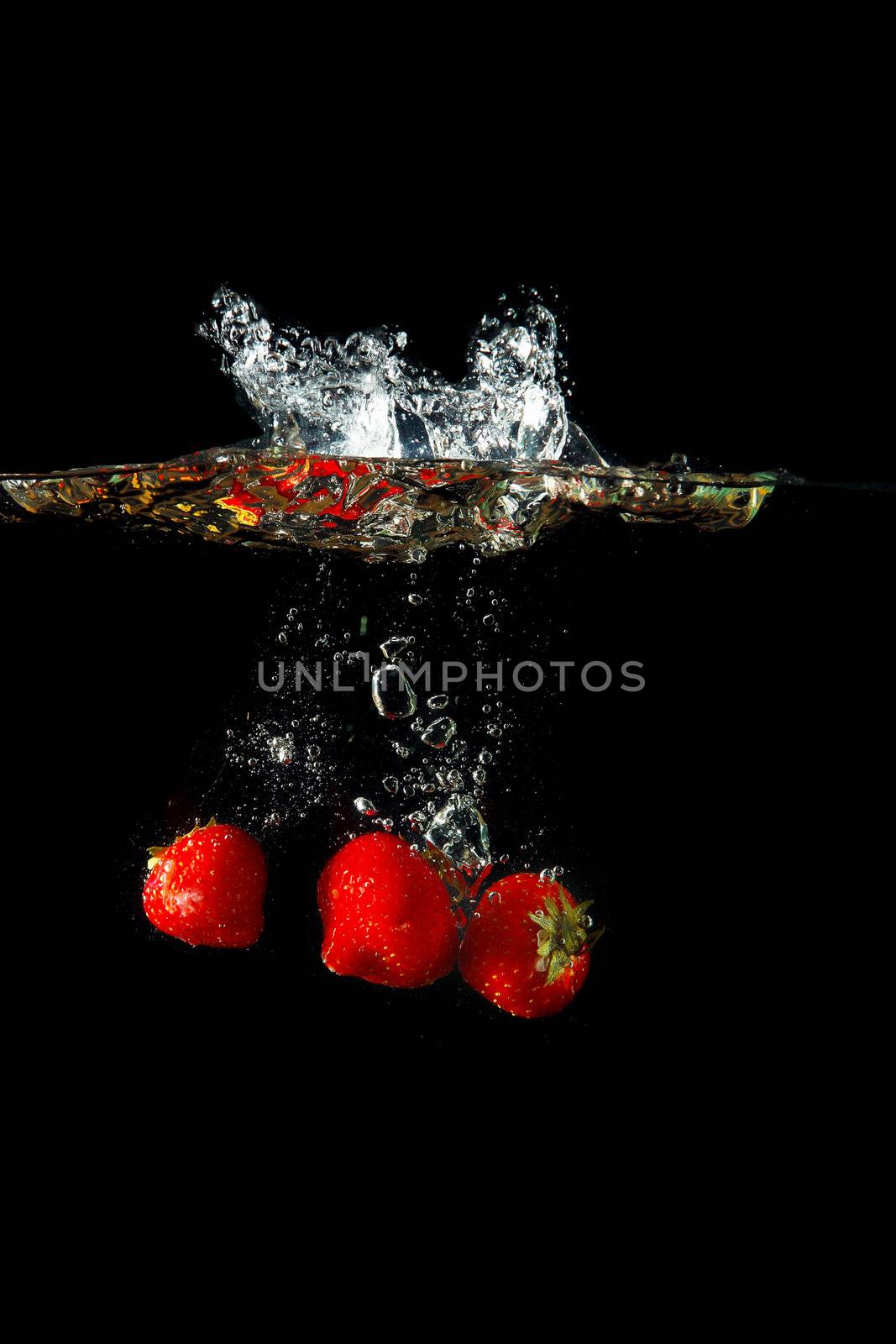 Colored red paprika in water splashes on black background