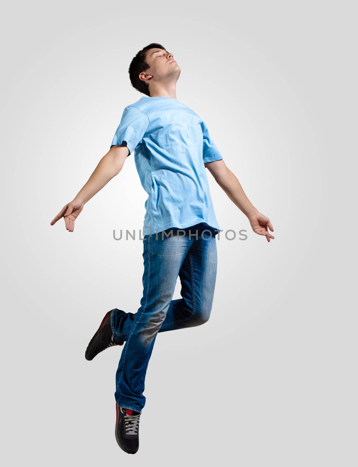 Modern slim hip-hop style man jumping dancing on a grey background