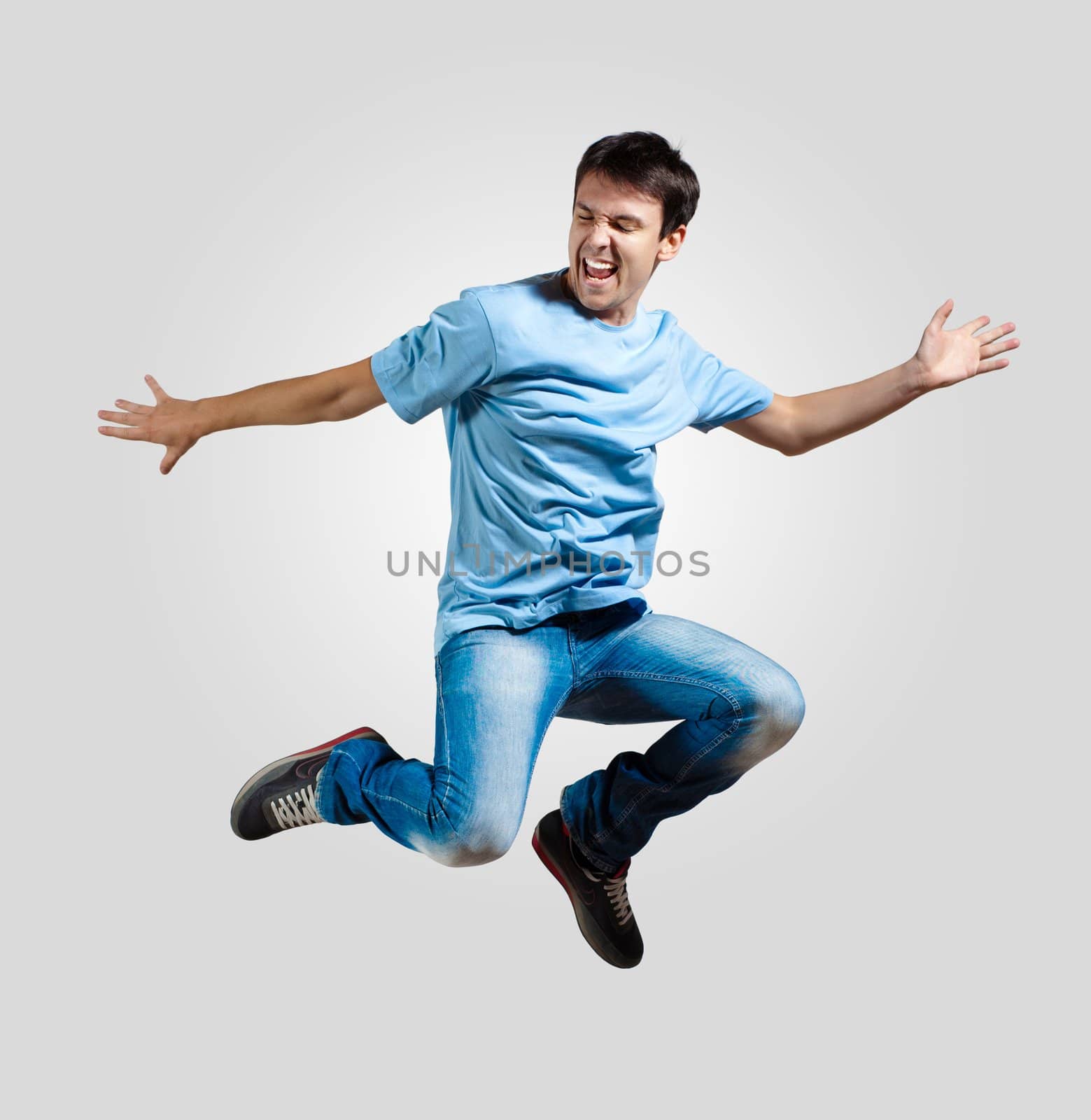 Modern slim hip-hop style man jumping dancing on a grey background