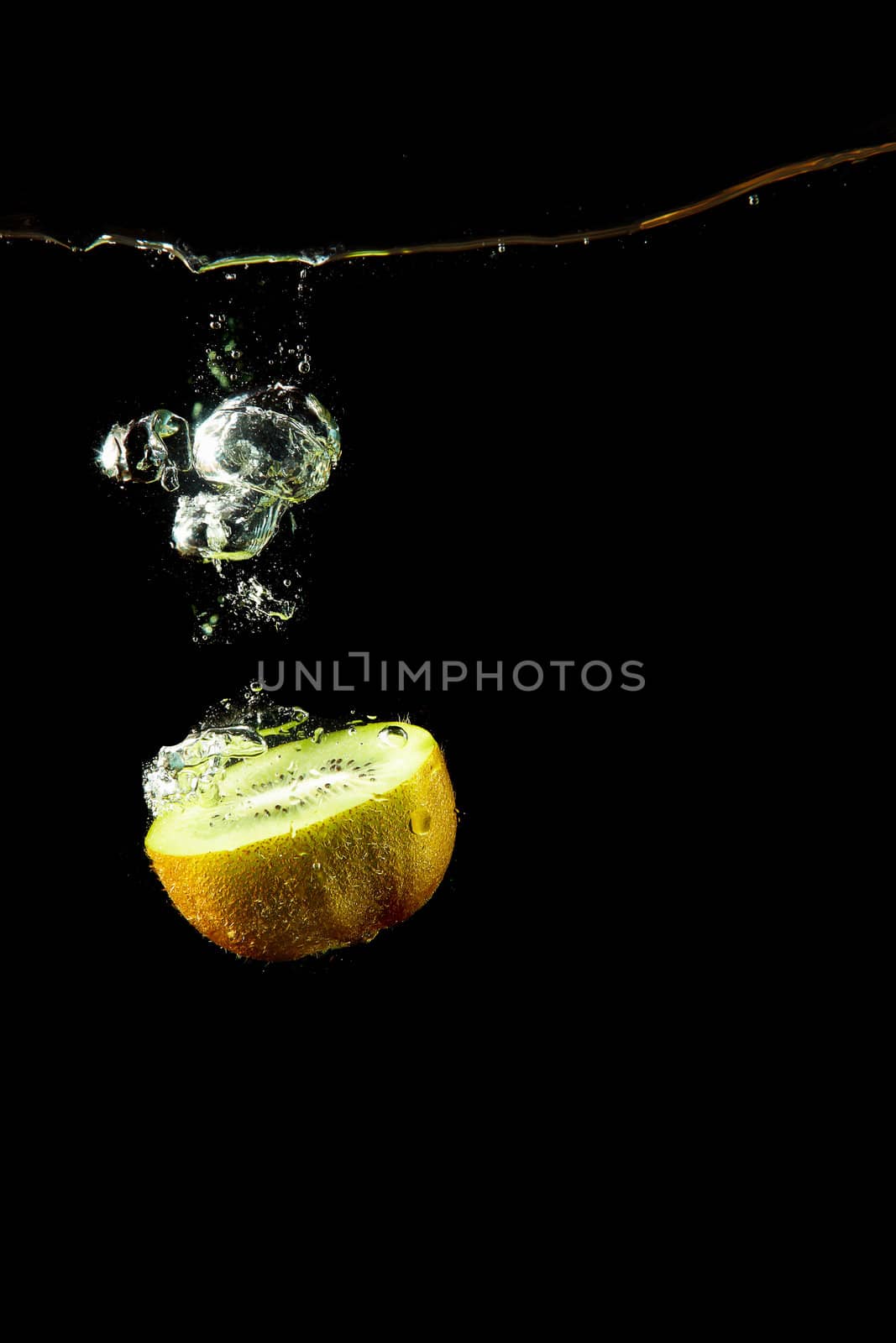 whole kiwi fruit o uder water on black background