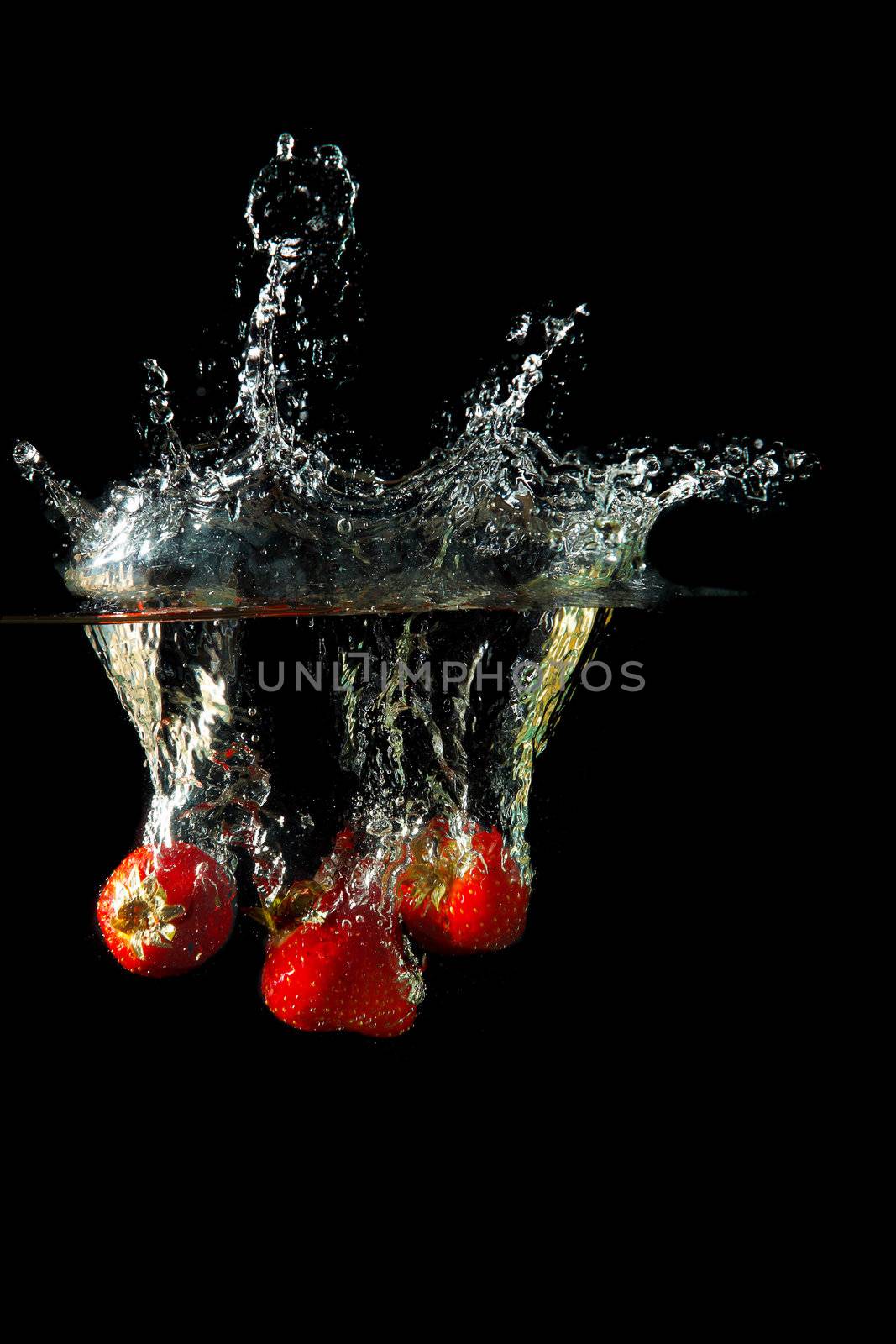 Colored red paprika in water splashes on black background