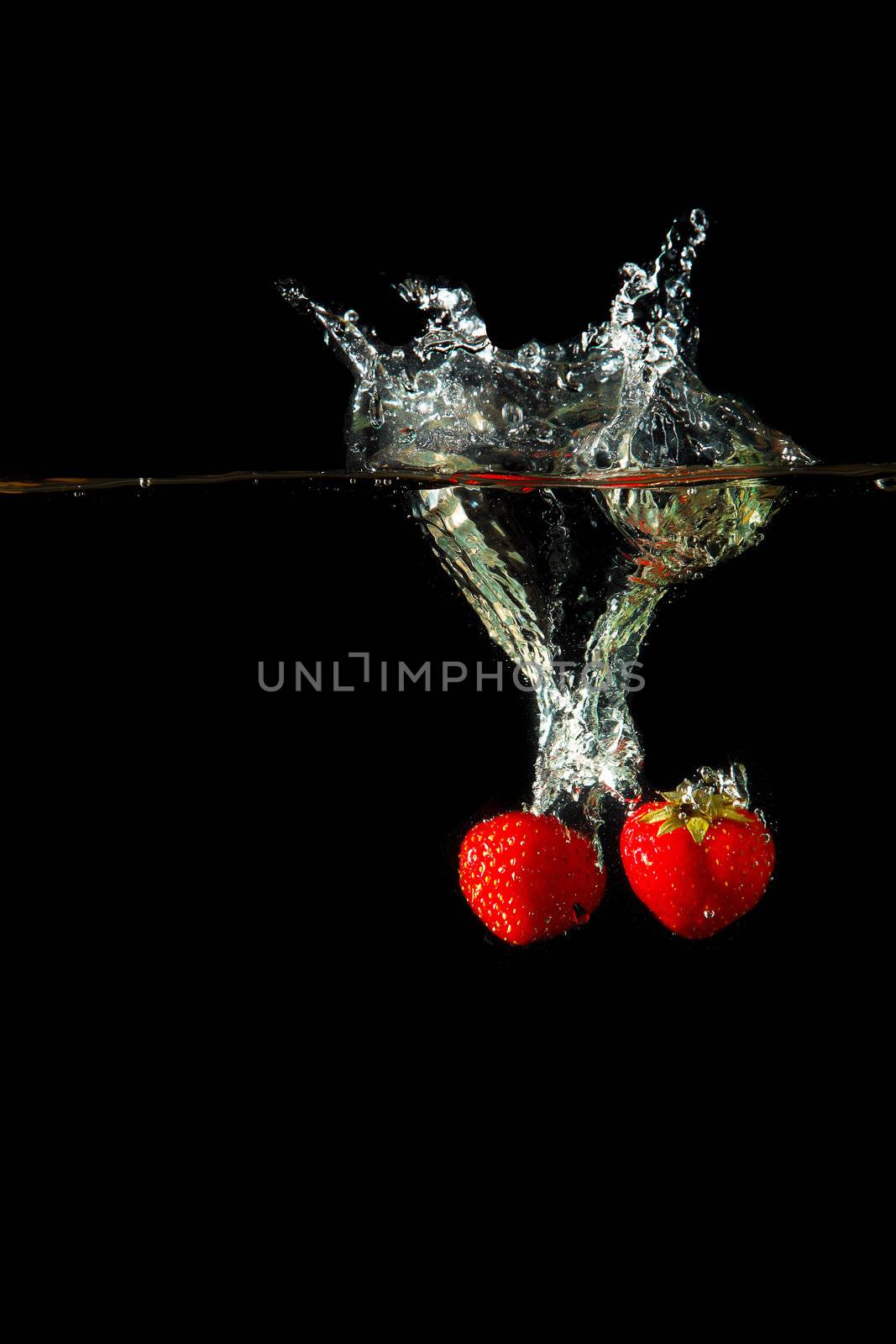 Colored red paprika in water splashes on black background