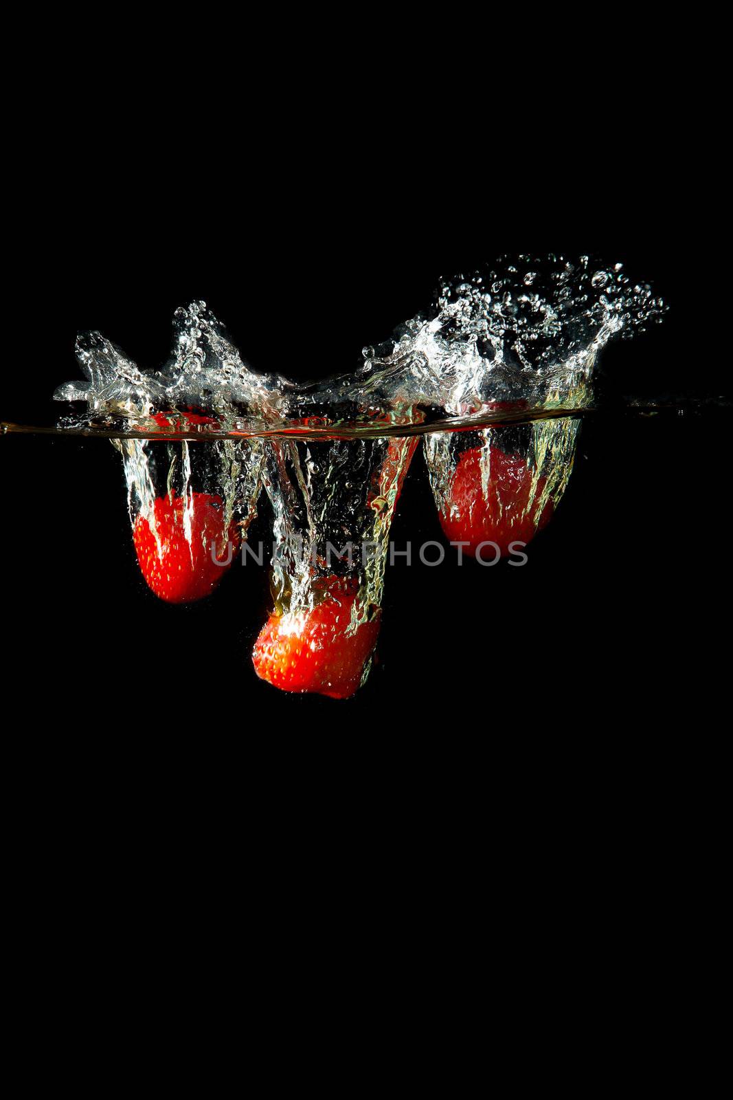 Colored red paprika in water splashes on black background