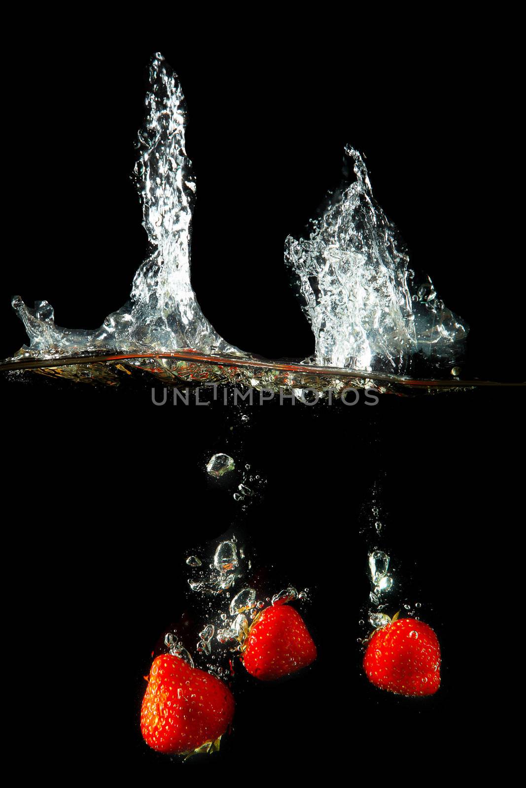 Colored red paprika in water splashes on black background