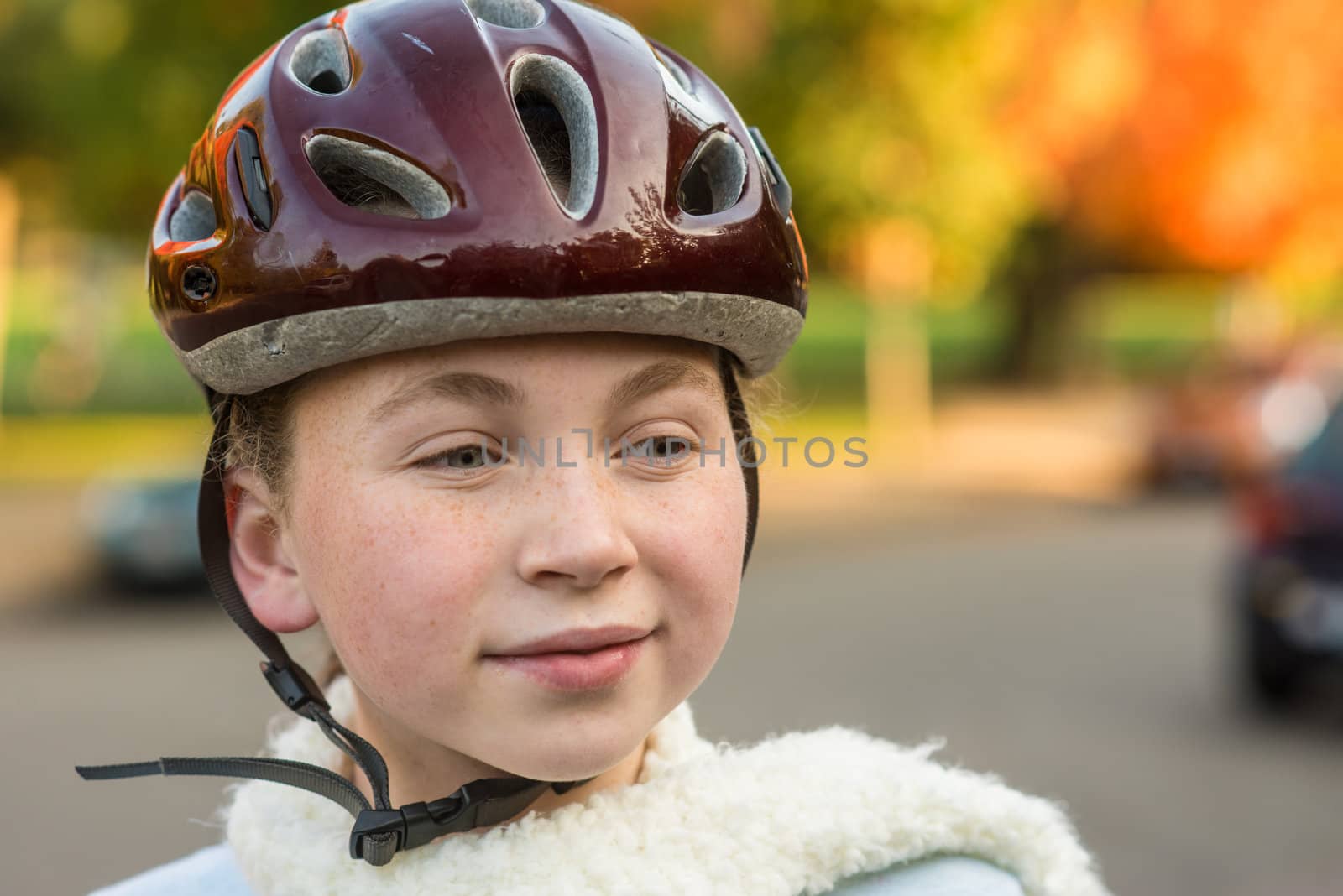 Young girl in fall wearing bicycle helmet by rongreer