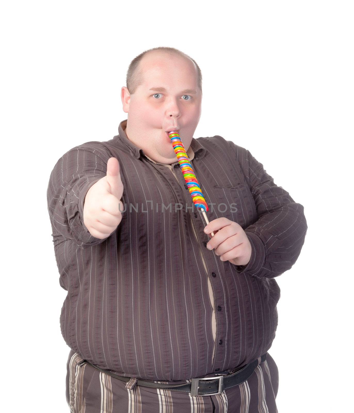 Fat obese man enjoying a a long colourful striped lollipop and showing thumb-up