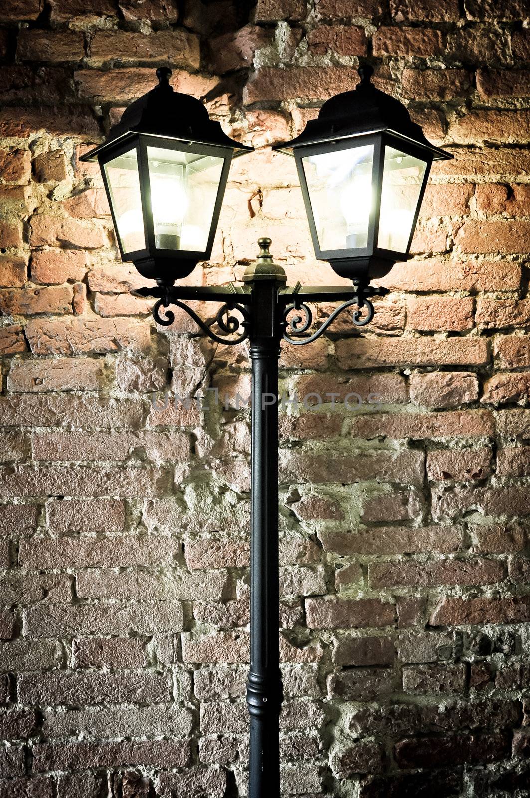 Detail of street lamp with structured old brick wall background