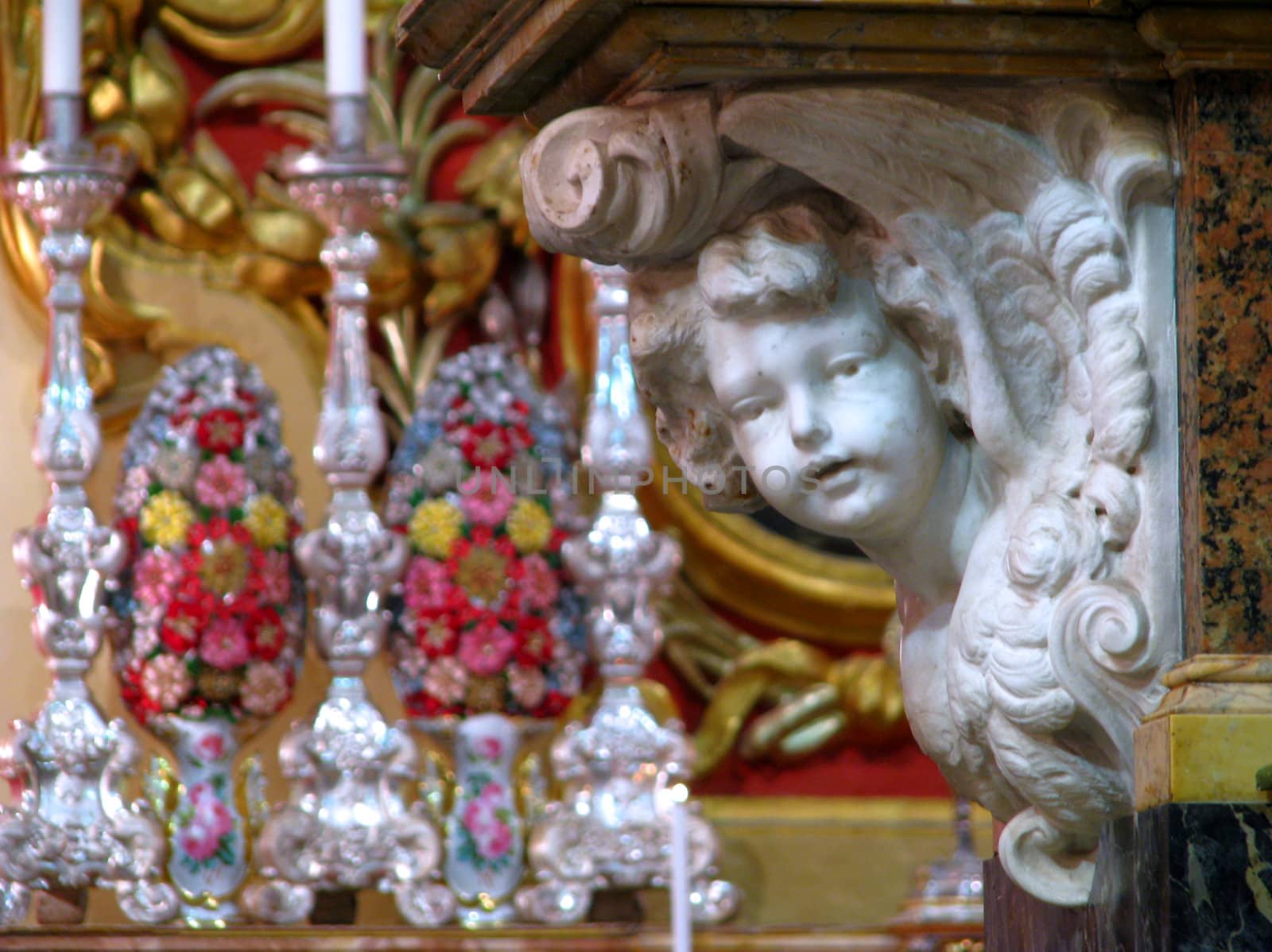 A marble angel with silver chandeliers in the background in Zejtun, Malta.