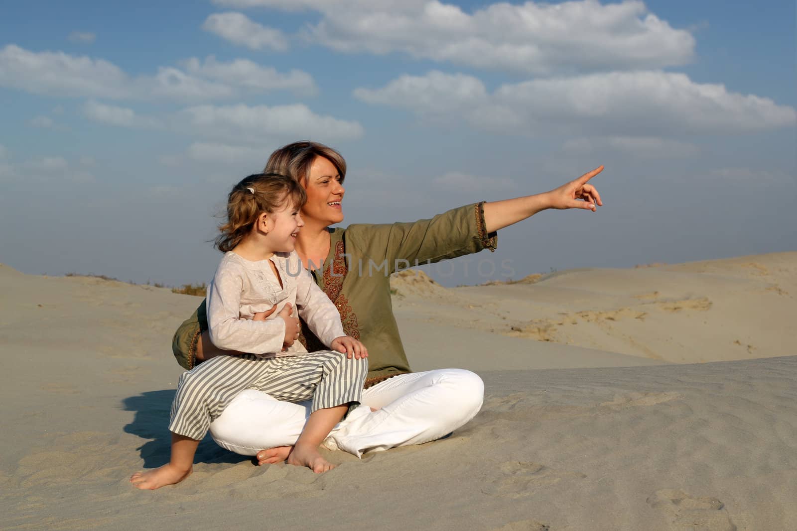 happy mother and daughter sitting on sand family scene by goce