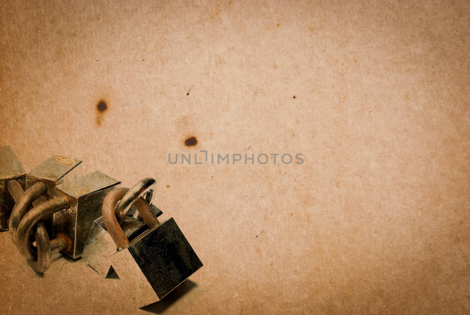Rusty old aged padlocks on vintage paper background