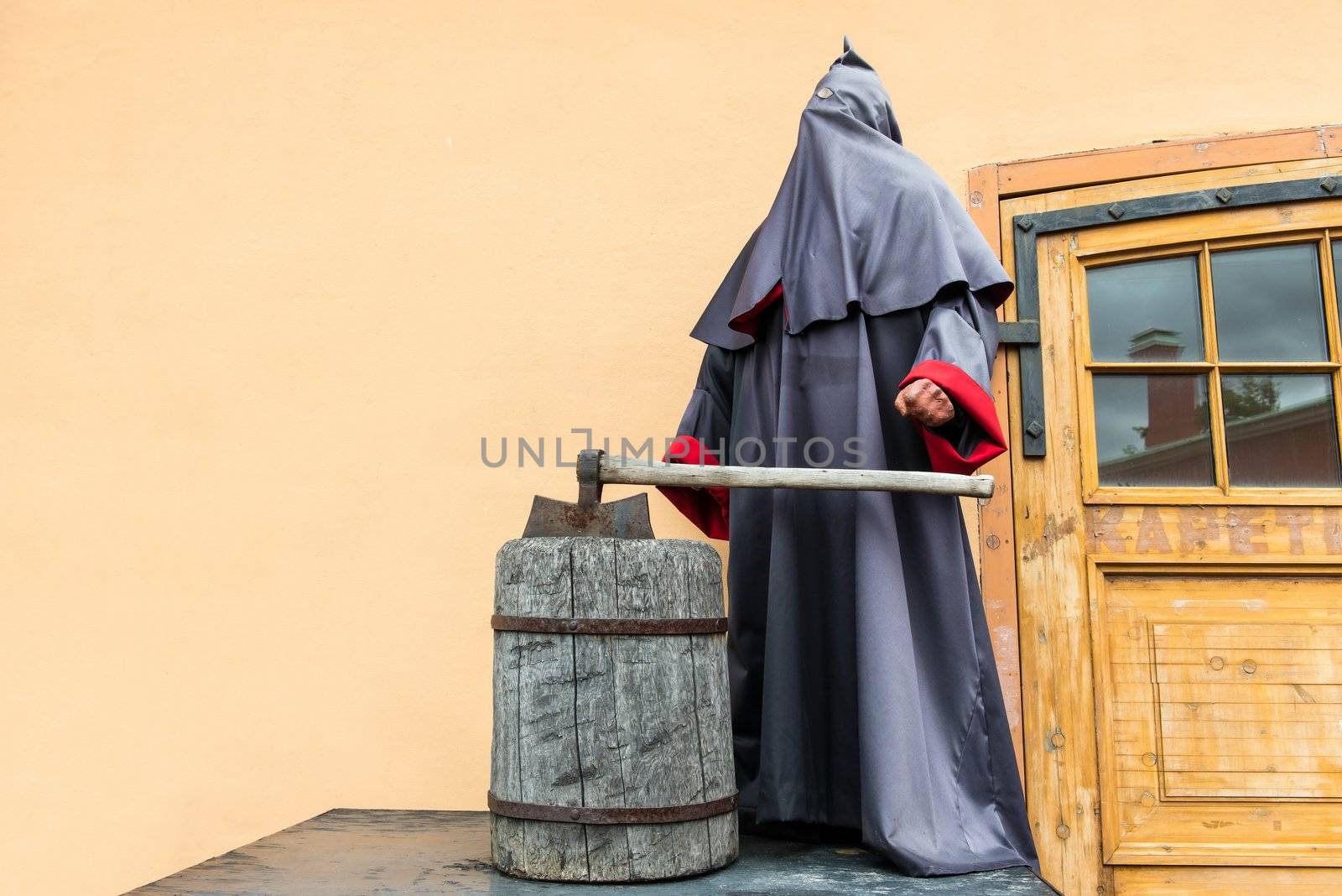 The grimmed reaper and executioner standing with a large axe on yellow wall