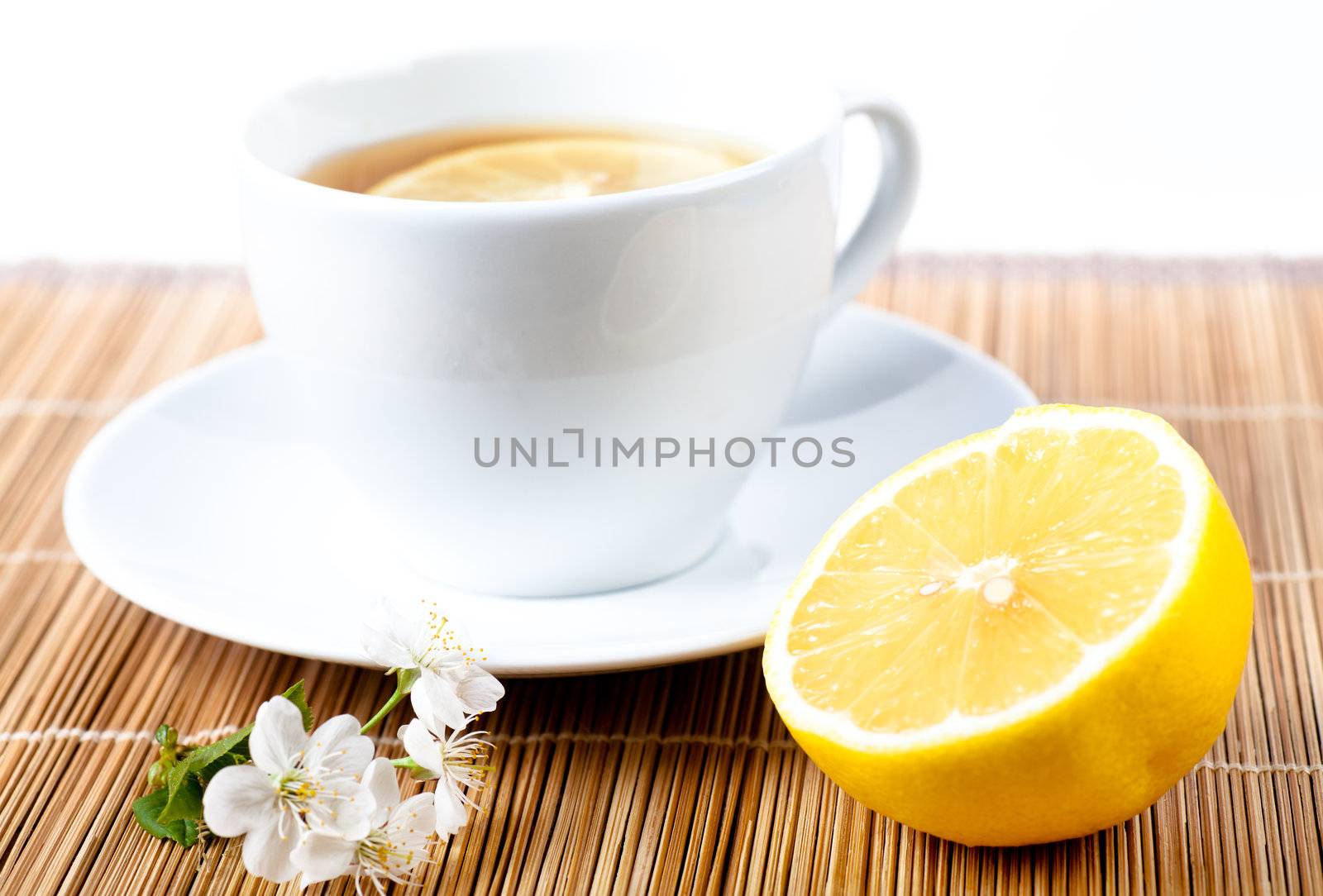 Tea in white cup with lemon and cherry flower