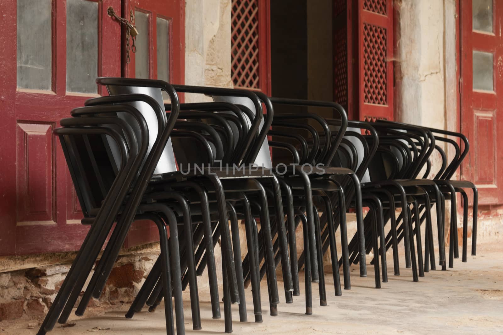 Many black metal chairs stacked on an old building