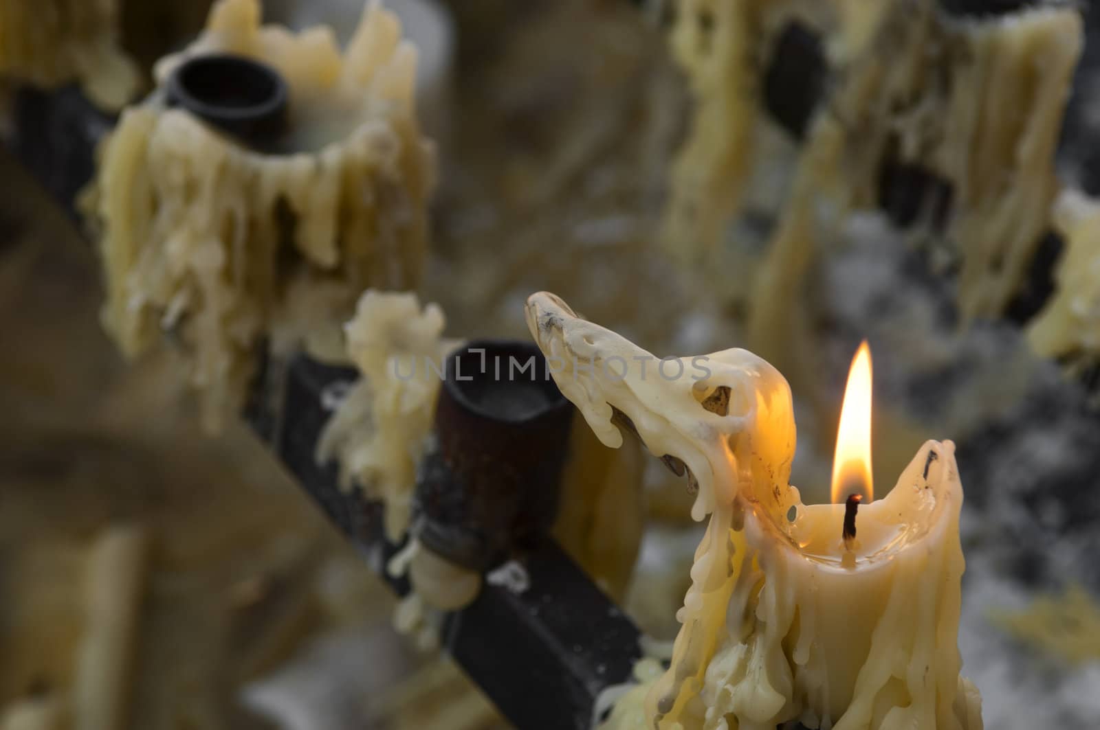 Votive burning candle in a candlestick and melted wax