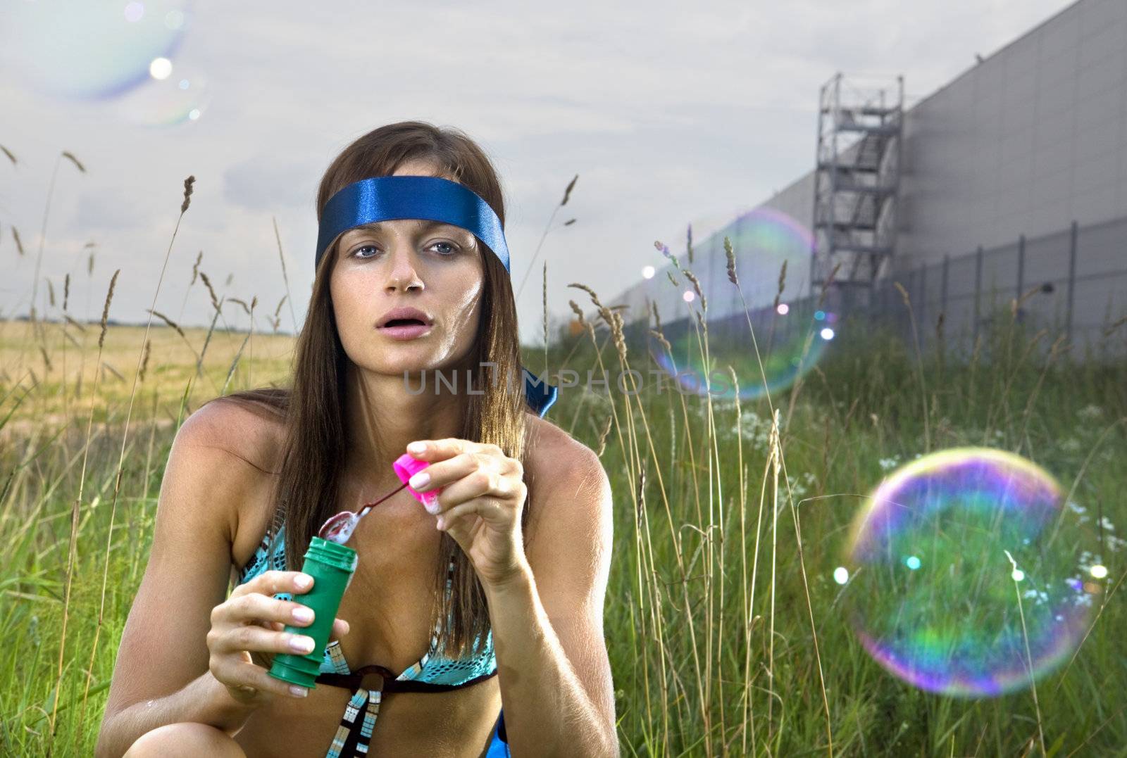 wistful young woman blowing soap bubbles in summer day